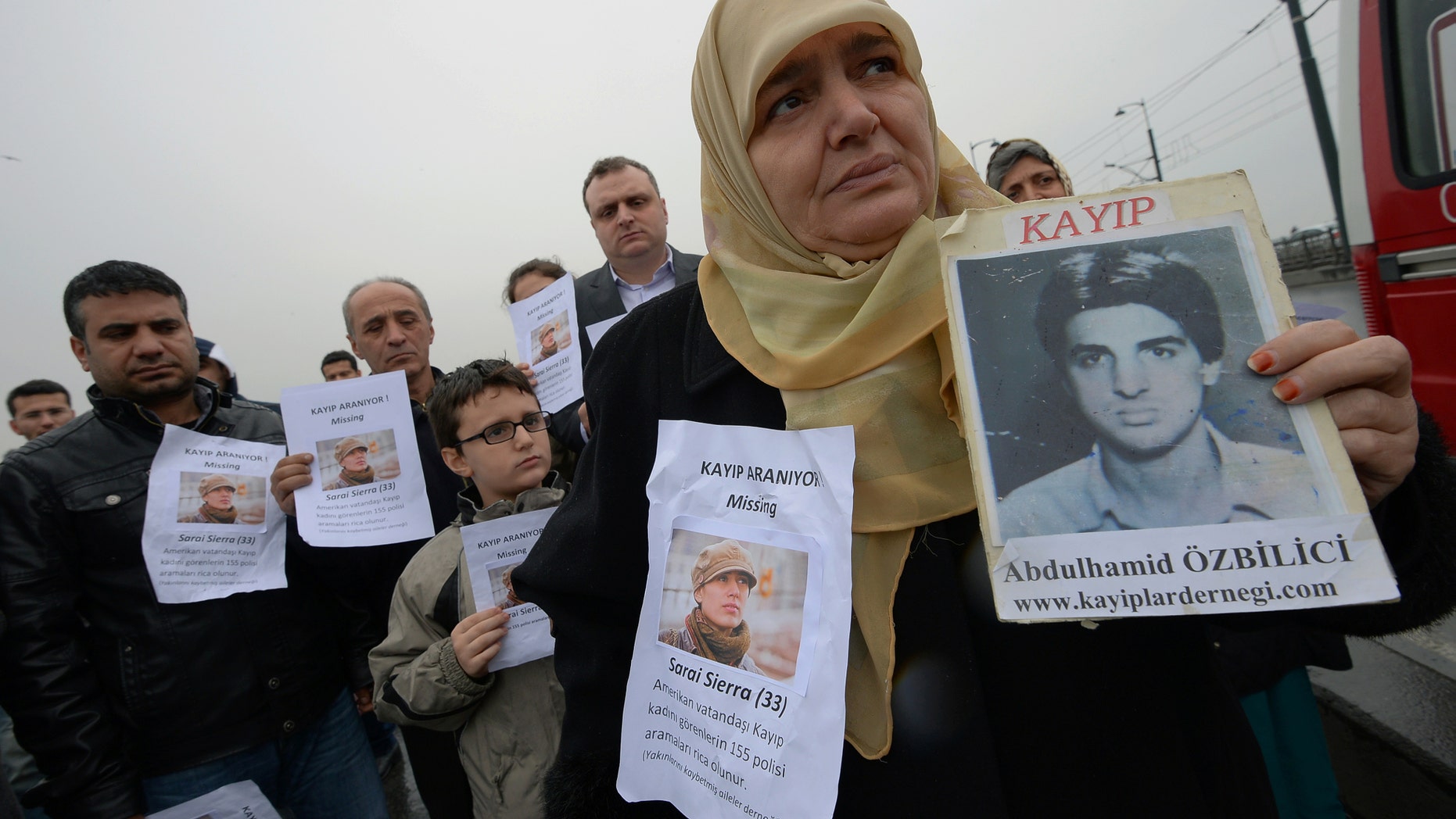 A Turkish mother shows a picture of her missing son as the members of the Istanbul-based Association For Families With Lost Relatives hand out flyers with photos of Sarai Sierra, a New York City woman who was found dead in Istanbul. (AP Photo)