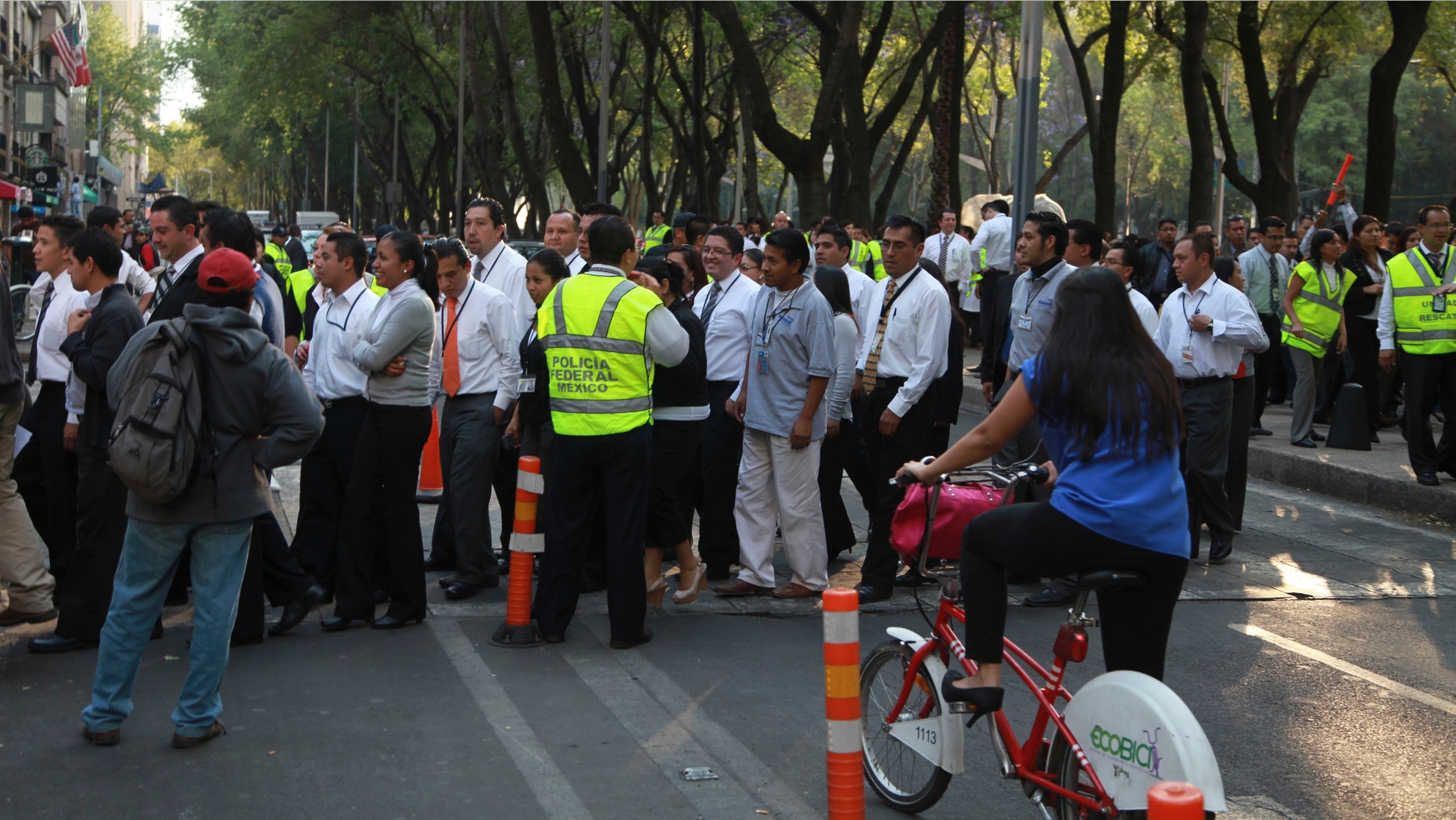 People begin returning to a building that was evacuated after an earthquake was felt in Mexico City, Mexico, Wednesday, April 11, 2012. The U.S. Geological Survey reported a preliminary reading of 7.0 magnitude for the quake, which it said was centered 238 miles (384 kilometers) west-southwest of Mexico City and 88 miles (143 kilometers) northwest of the Pacific resort of Zihuantanejo. (AP Photo/Dario Lopez-Mills)