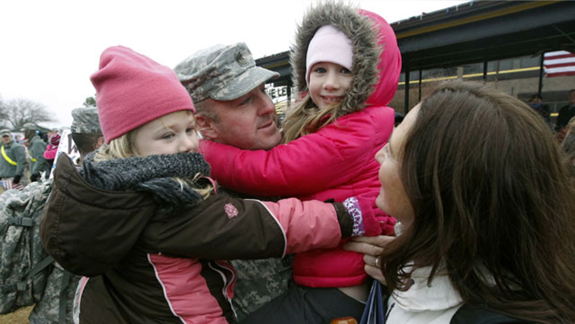 December 24, 2011: Sgt. Scott Dawson holds his daughters Mia, 5, left, and Victoria, 7, with his wife, Capt. Jessica Dawson, as U.S. Army 1st Cavalry 3rd Brigade soldiers return home from deployment in Iraq, on Christmas Eve at Fort Hood, Texas.
