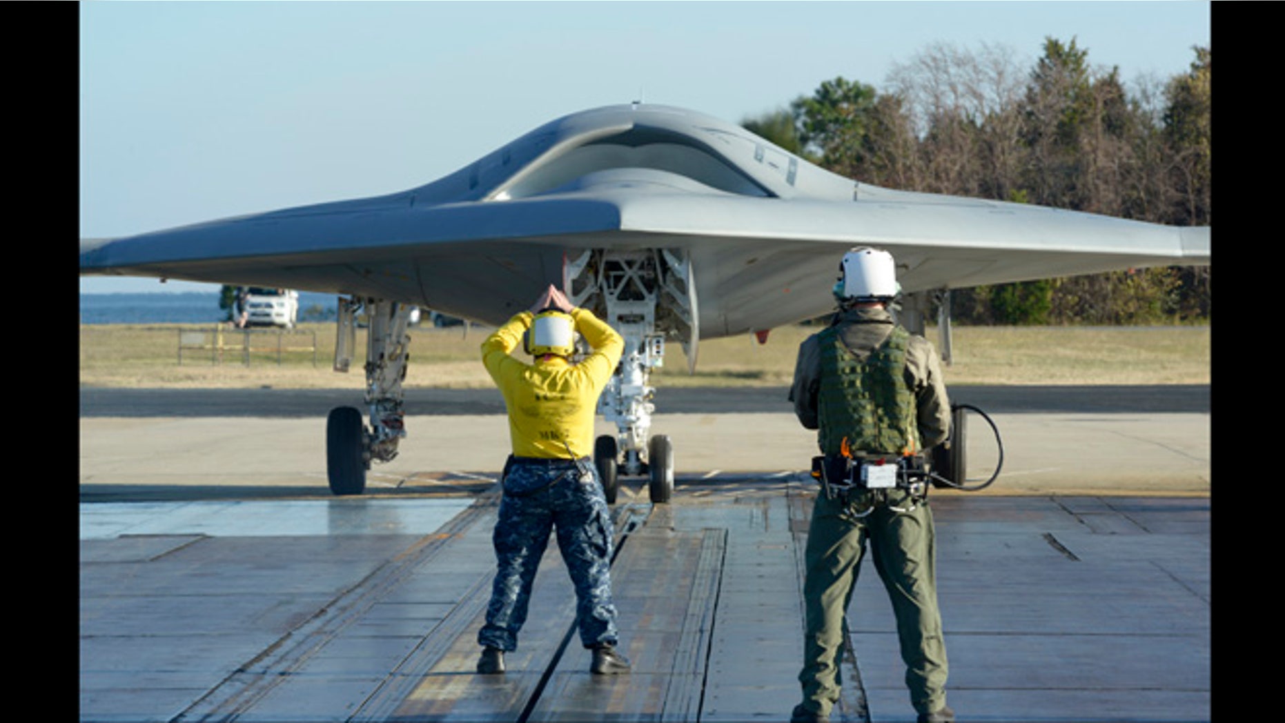 Nov. 29, 2012: In preparation for the first catapult launch of the U.S. Navy's X-47B unmanned aircraft, a flight deck director - aka "yellow shirt" - and a deck operator using Northrop Grumman's wireless, handheld Control Display Unit guide the aircraft into position on a shore-based catapult at Naval Air Station Patuxent River, Md.