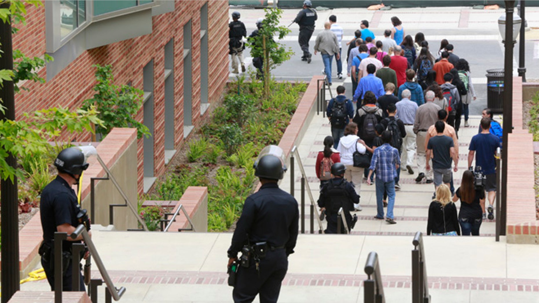 Los Angeles Police officers escort people at the UCLA campus after a fatal shooting at the University of California, Los Angeles, Wednesday, June 1, 2016, in Los Angeles. Los Angeles police chief says shooting at UCLA was murder-suicide. (AP Photo/Damian Dovarganes)