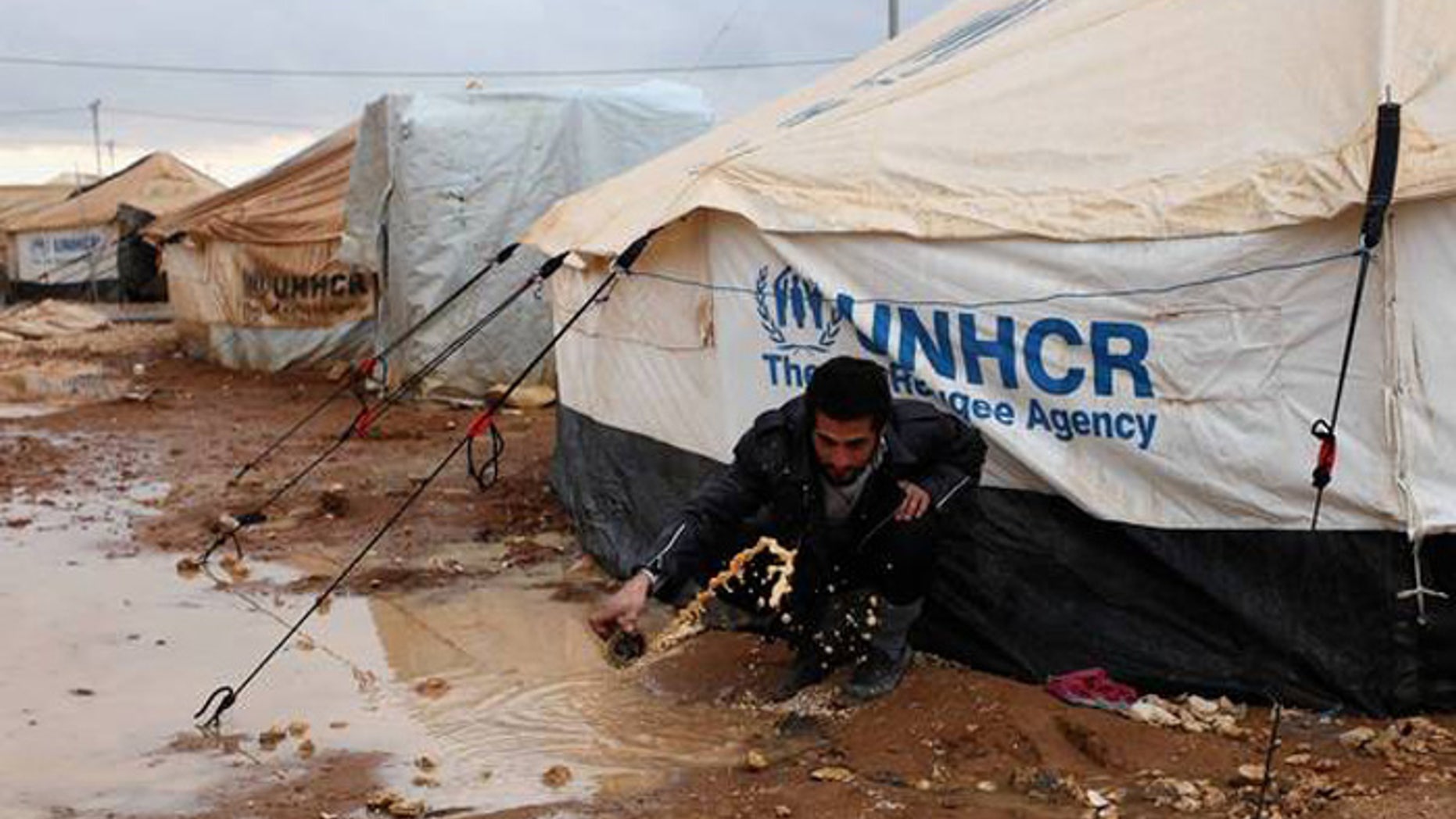 A Syrian refugee removes water and mud around his UN-supplied tent, at Zaatari Syrian refugee camp, near the Syrian border in Mafraq, Jordan. (AP Photo/Mohammad Hannon)