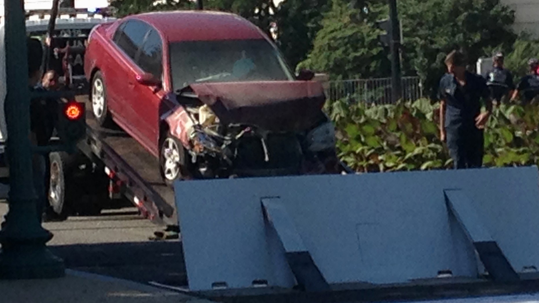 A car is is moved after crashing into a barrier on Capitol Hill in Washington, Friday, July 31, 2015.
