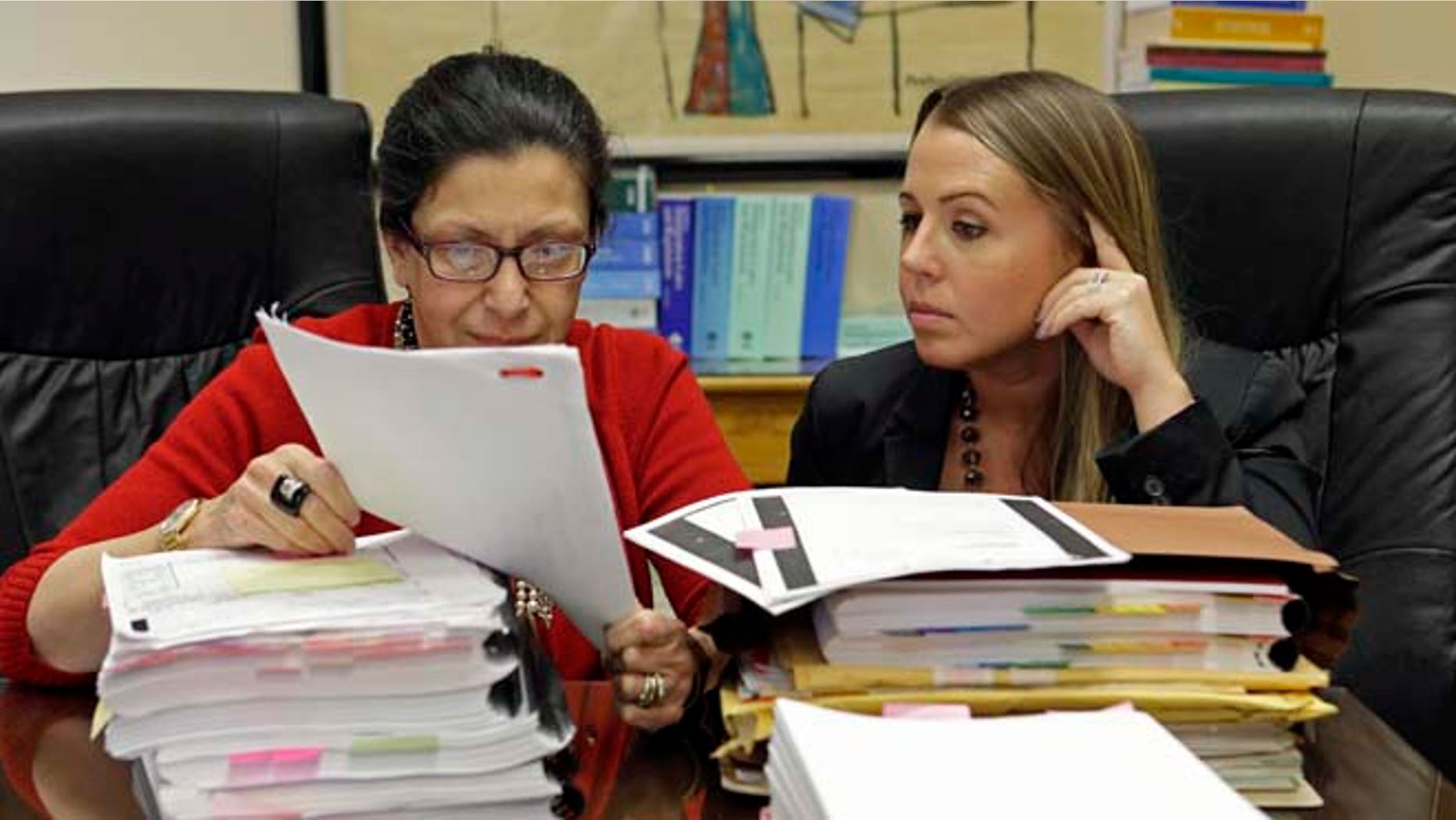 Attorneys Grisel Ybarra and Monica Barba Neumann look over documents at their office in Miami, on July 16, 2015.