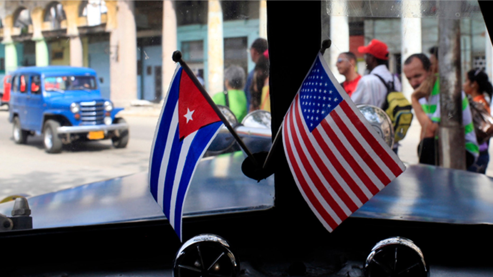 FILE - In this March 22, 2013 file photo, miniature flags representing Cuba and the U.S. are displayed on the dash of an American classic car in Havana, Cuba. The Obama administration is putting a large dent in the U.S. embargo against Cuba as of Friday, significantly loosening restrictions on American trade and investment. The new rules also open up the communist island to greater American travel and allow U.S. citizens to start bringing home small amounts of Cuban cigars after more than a half-century ban. (AP Photo/Franklin Reyes, File)