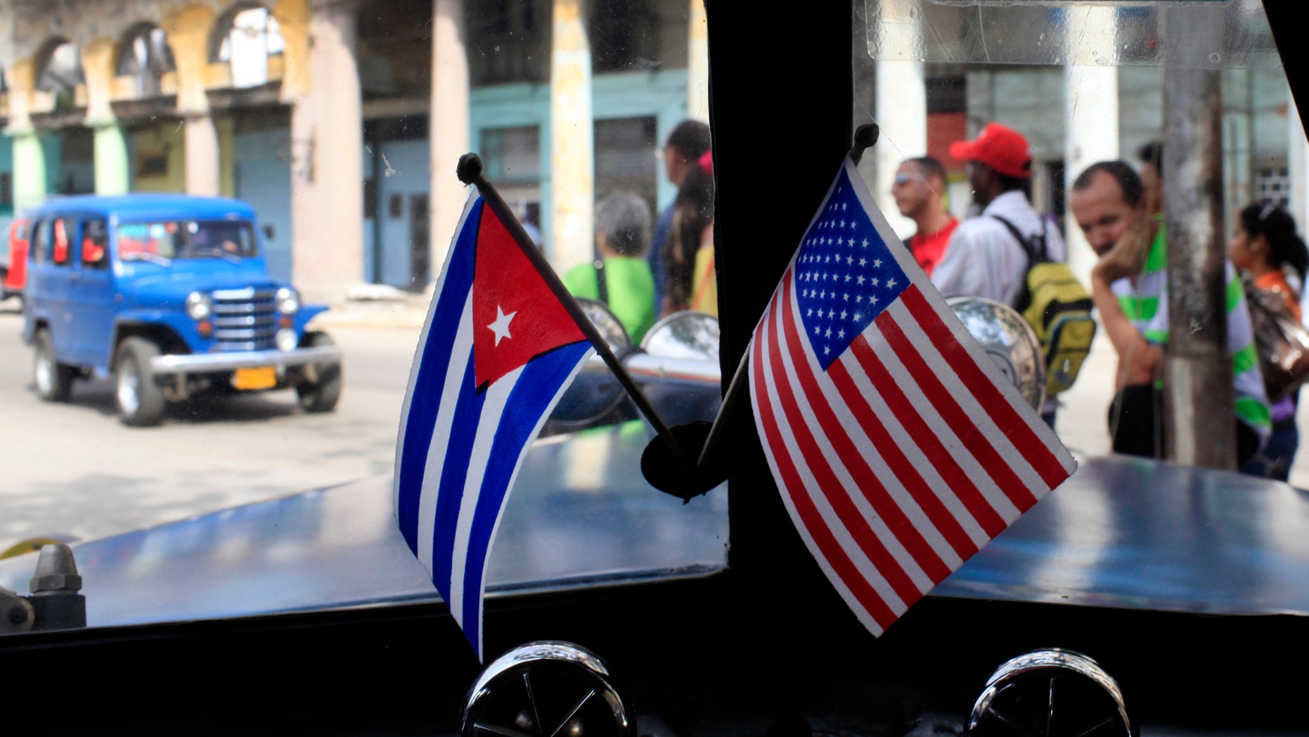 FILE - In this March 22, 2013 file photo, miniature flags representing Cuba and the U.S. are displayed on the dash of an American classic car in Havana, Cuba. The Obama administration is putting a large dent in the U.S. embargo against Cuba as of Friday, significantly loosening restrictions on American trade and investment. The new rules also open up the communist island to greater American travel and allow U.S. citizens to start bringing home small amounts of Cuban cigars after more than a half-century ban. (AP Photo/Franklin Reyes, File)
