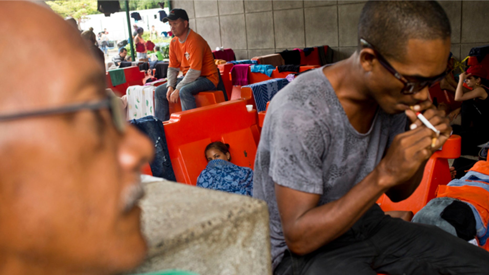 Cuban migrants sit outside the immigration office in Peñas Blancas, Costa Rica, Tuesday, Nov. 17, 2015. More than 1,000 Cuban migrants heading north to the United States tried to cross the border from Costa Rica into Nicaragua, causing tensions to soar between the neighbors as security forces sought to turn them back. Nicaragua's government responded furiously on Sunday with a statement saying that Costa Rica "had deliberately and irresponsibly thrown, and continues to throw" the Cuban migrants into its territory, violating its national sovereignty. (AP Photo/Esteban Felix)