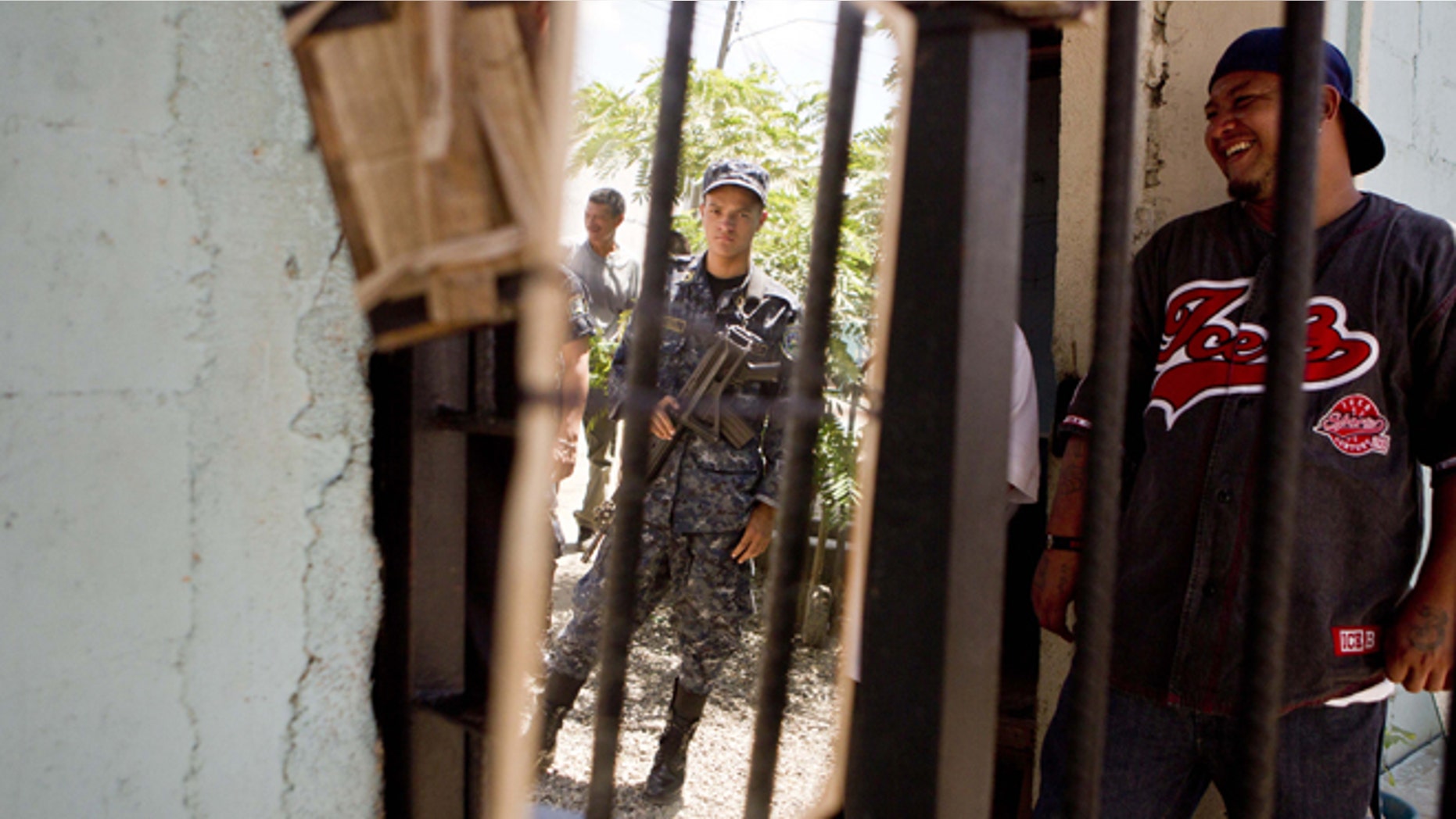 A National Police officer is reflected in a mirror hanging inside the area of gang members from the Mara Salvatrucha, MS, inside the San Pedro Sula prison in Honduras, Tuesday, May 28, 2013. Honduras' largest and most dangerous street gangs have declared a truce, offering the government peace in exchange for rehabilitation and jobs. A Mara Salvatrucha gang spokesman says the gang and its rival, 18th Street, will commit to zero violence and zero crime in the streets as first step show of good faith. (AP Photo/Esteban Felix)
