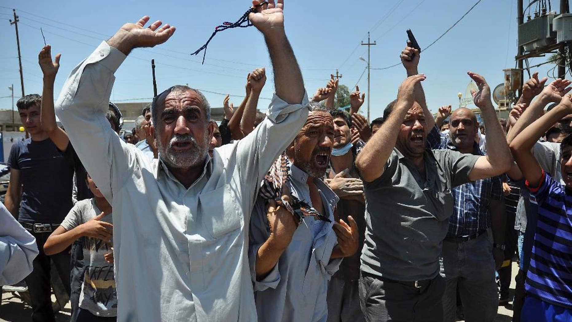 In this June 23, 2014, photo, mourners chant slogans against the al-Qaida breakaway group Islamic State of Iraq and the Levant after they bury 15 bodies in the village of Taza Khormato near the northern oil-rich city of Kirkuk, Iraq. U.S. teams of special forces going into Iraq after a three-year gap will face an aggressive insurgency, a splintering military and a precarious political situation as they help Iraqi security forces improve their ability to battle Sunni militants. (AP Photo/Emad Matti)