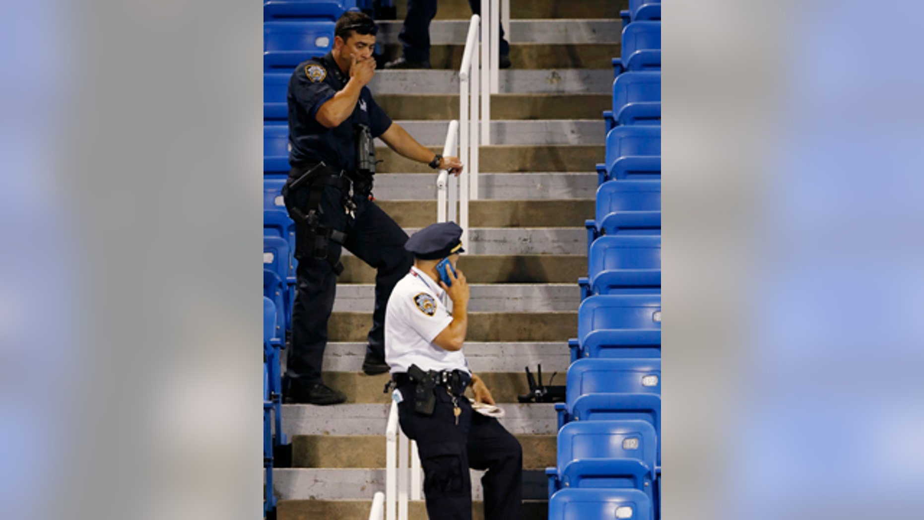 Sept. 3, 2015: Police officers investigate the southwest corner of Louis Armstrong Stadium after a drone flew over the court, buzzing the players during a match between Flavia Pennetta and Monica Niculescu during the second round of the U.S. Open tennis tournament in New York. The drone crashed into the seats and can be seen to the right of the police officer on his phone. (AP Photo/Kathy Willens)