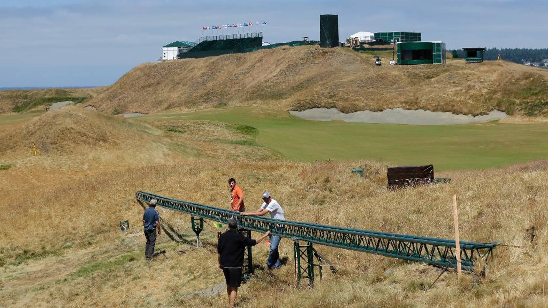 Technicians adjust a long video camera slider rail Thursday, June 11, 2015, on the 18th hole at Chambers Bay golf course in University Place, Wash. In its bid to take over the U.S. Open from NBC, Fox promised innovative coverage and will feature new graphics and cameras as the network broadcasts the tournament for the first time next week. (AP Photo/Ted S. Warren)