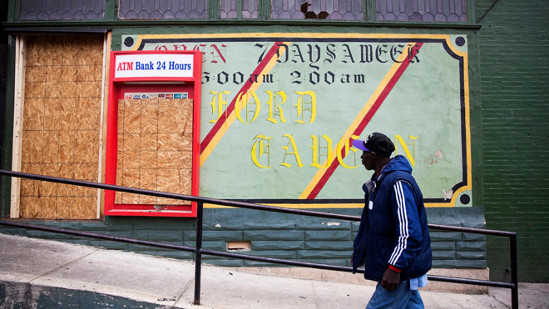 FILE - In this April 30, 2015 file photo, a man walks past the damaged Oxford Tavern in Baltimore. In a presidential campaign where candidates are jockeying to be champions of the middle class and courting donations from the wealthy, the poor are inching their way into the debate. Tensions in Baltimore, Ferguson, Missouri, and elsewhere have sparked examinations of the relationship between poor communities and the police, as well as the systemic problems that have trapped many of the 45 million Americans living in poverty. But addressing the economic, education, and security issues that have plagued underprivileged neighborhoods for decades remains a politically elusive challenge. (AP Photo/David Goldman, File)