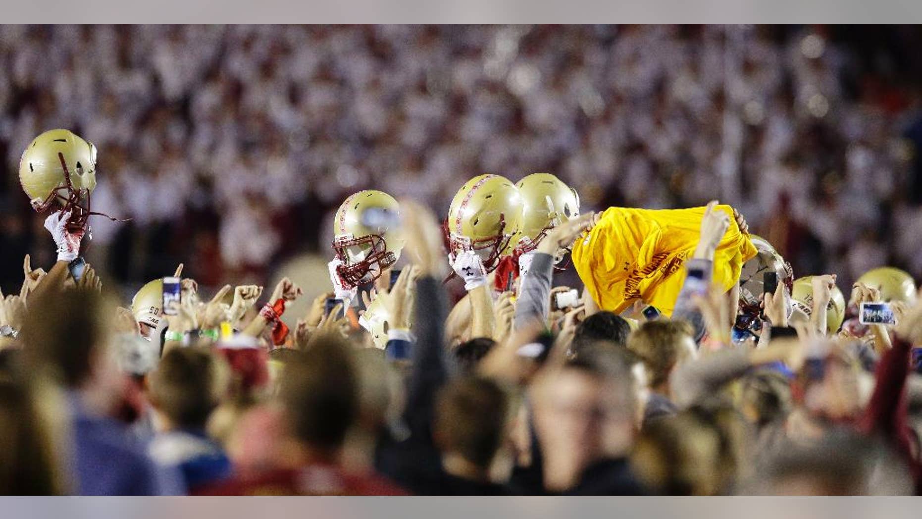 Celebrating members of the Boston College team, holding their helmets above their heads, are surrounded by celebrating fans after they defeated Southern California in their NCAA college football game Saturday, Sept. 13, 2014 in Boston. Boston College defeated USC 37-3. (AP Photo/Stephan Savoia)
