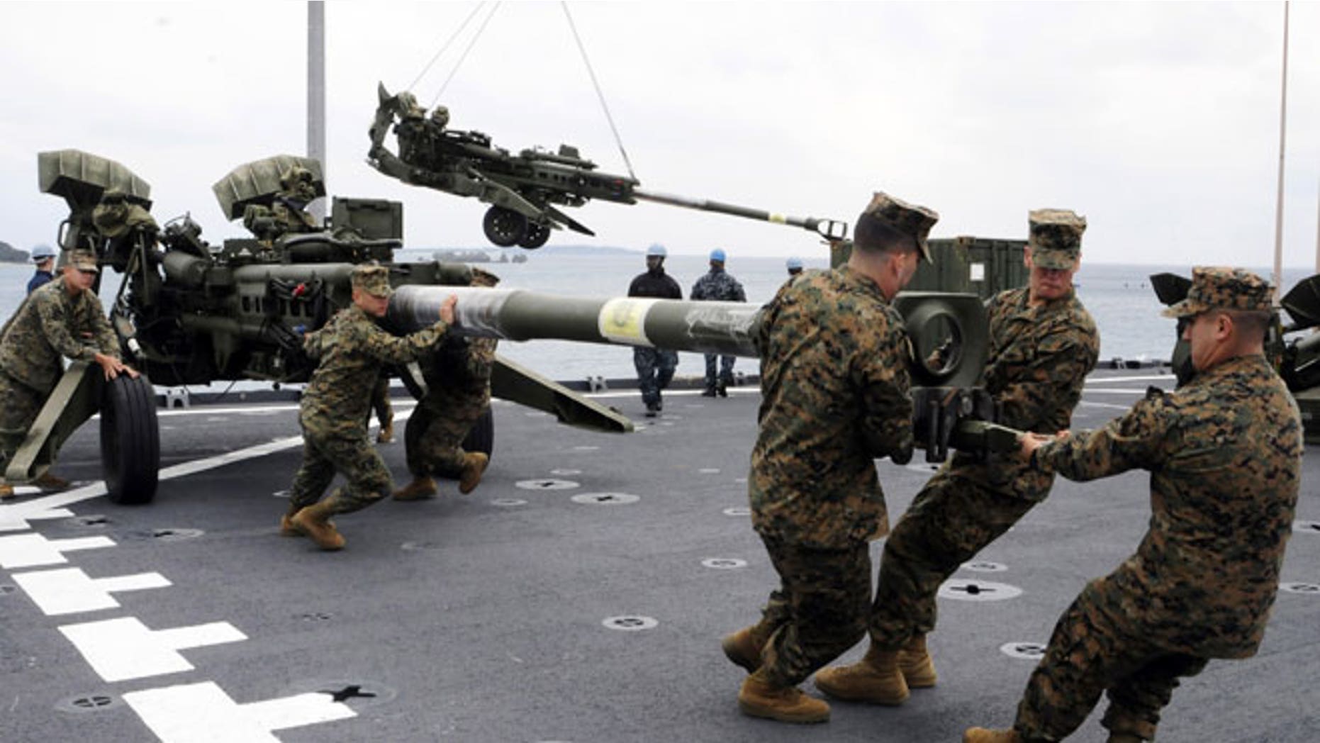 In this Feb. 2, 2012 file photo released by U.S. Navy, U.S. Marines assigned to the 31st Marine Expeditionary Unit haul a 155 mm Howitzer onto the flight deck of the forward-deployed amphibious dock landing ship USS Germantown in Okinawa, Japan, when the ship pulled into Okinawa to embark the Marines in preparation of exercise Cobra Gold 2012.
