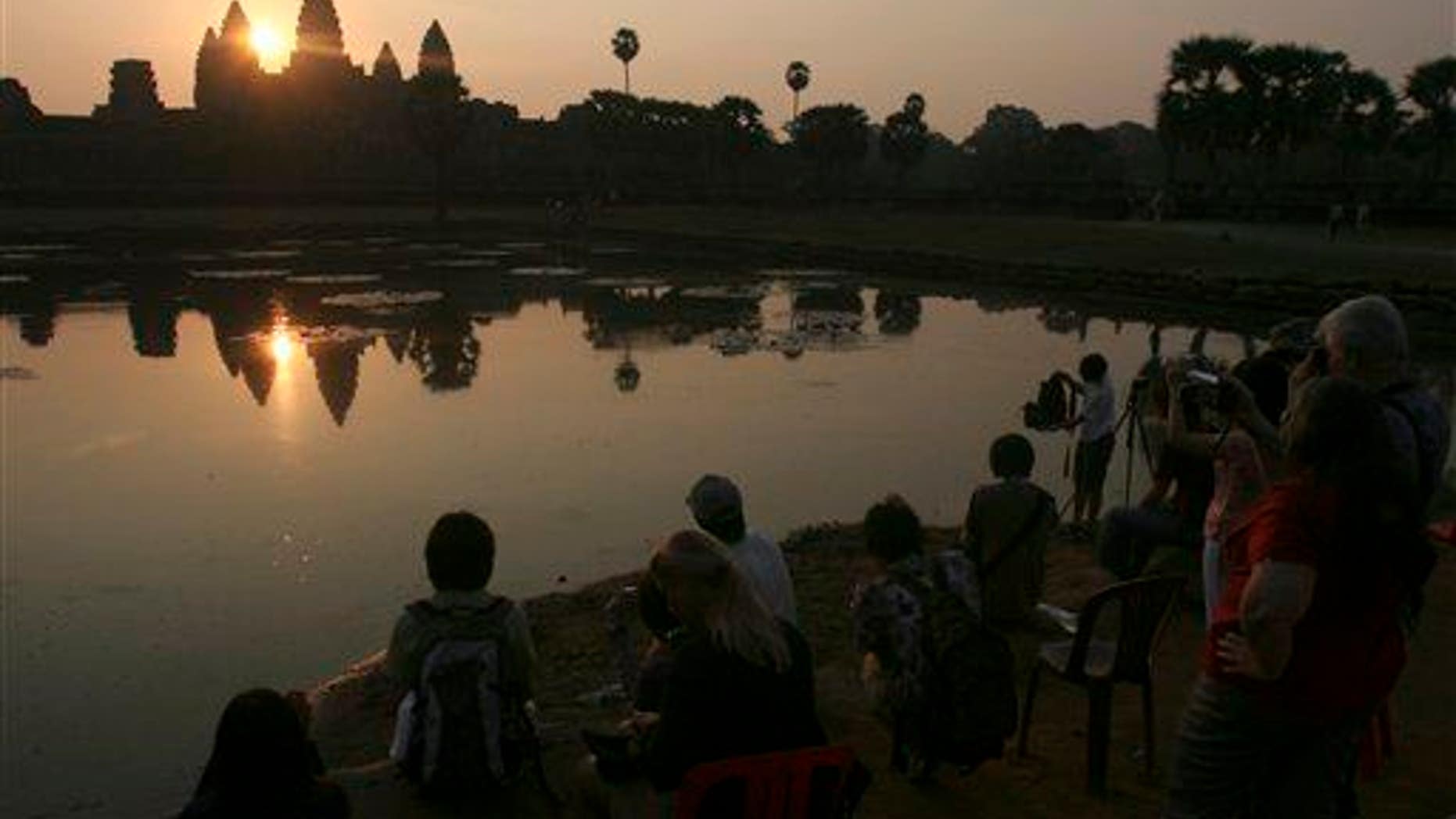 In this March 30, 2008 photo, tourists watch the sunrise at the famed Angkor Wat temple in Siem Reap province, Cambodia.