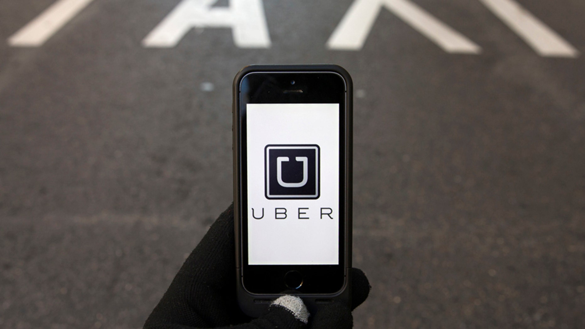 File photo - The logo of car-sharing service app Uber on a smartphone over a reserved lane for taxis in a street is seen in this photo illustration taken in Madrid on Dec. 10, 2014.