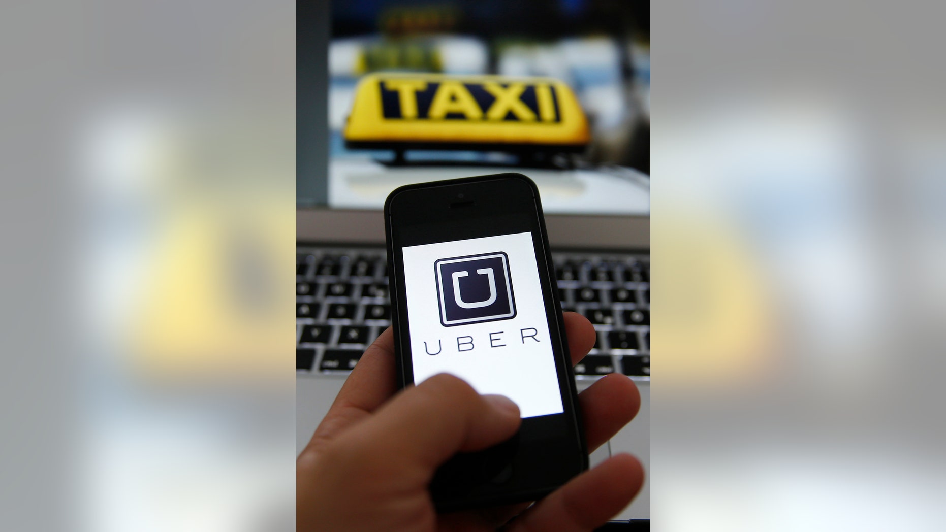 An illustration picture shows the Uber logo on a smartphone next to the picture of an official German taxi sign in Frankfurt, Sep. 15, 2014.