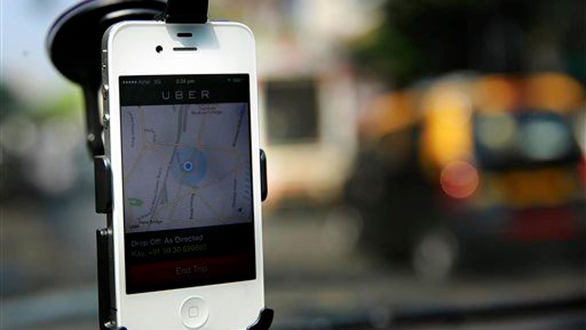 In this 2014 photo, a smartphone is mounted on the glass of an Uber car in Mumbai, India.