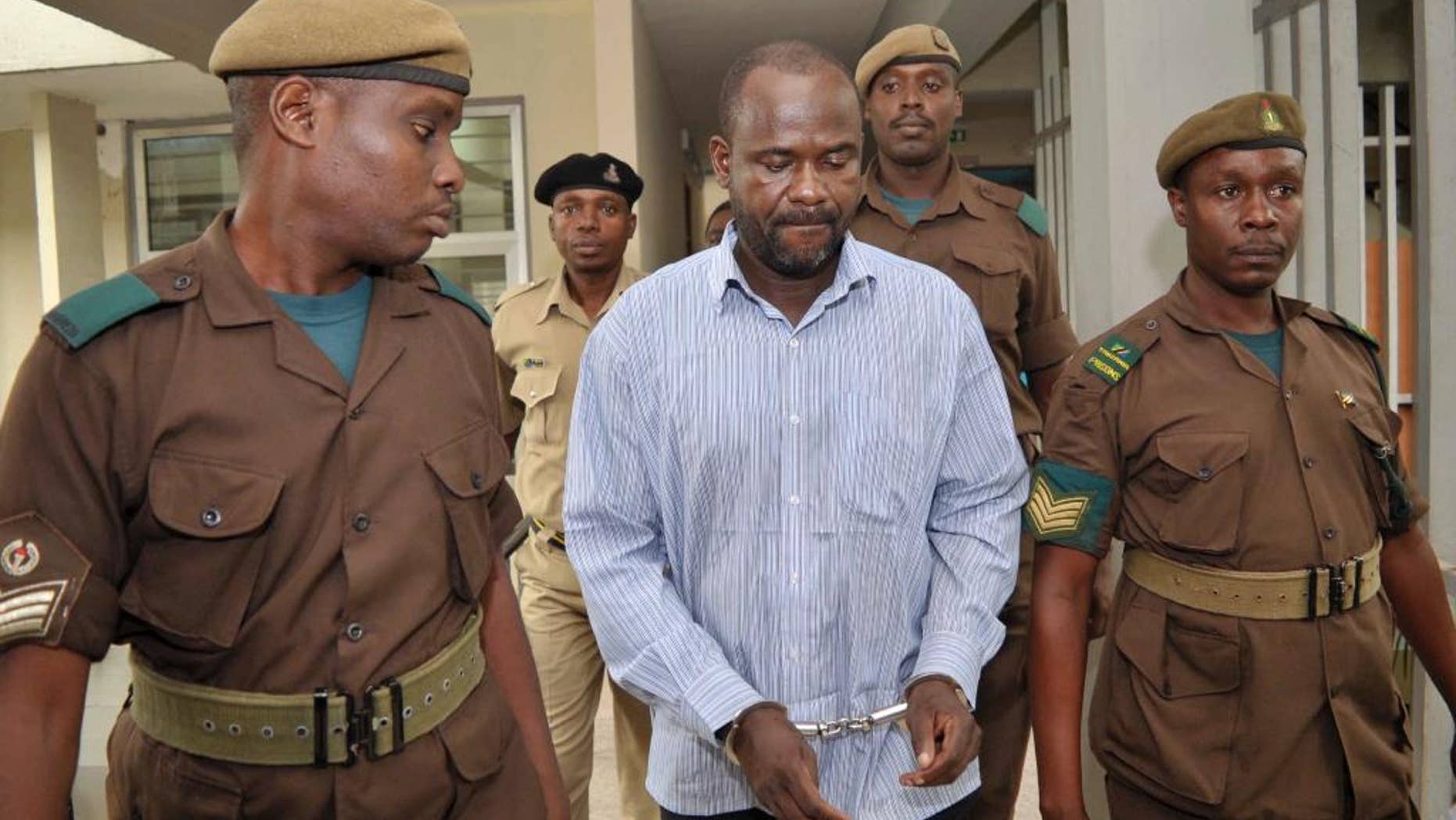 FILE - In this Friday, May 22, 2015 file photo, rebel leader of the Ugandan Allied Democratic Forces (ADF), Jamil Mukulu, center, is escorted by prison wardens as he appears at a magistrates court to challenge extradition proceedings against him, in Dar es Salaam, Tanzania. The head of Interpol in Uganda said Friday, July 10, 2015, that Mukulu, a most-wanted Ugandan extremist who is accused of committing atrocities in Uganda and Congo, has been extradited to Uganda. (AP Photo/Khalfan Said, File)