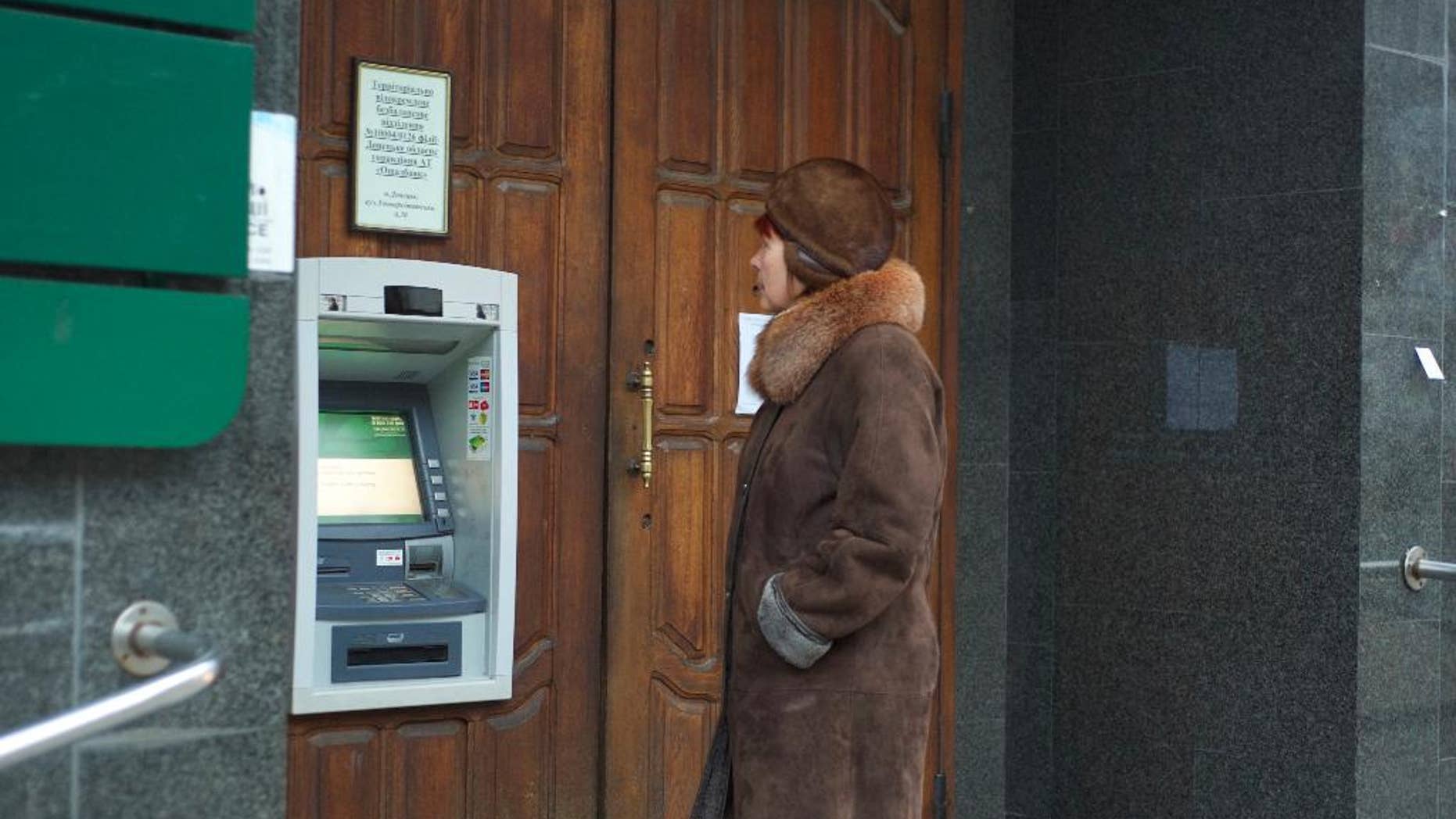 A woman stands at an ATM that doesn't work outside a Ukrainian bank in Donetsk, eastern Ukraine, Tuesday, Nov. 25, 2014. Money is running short in the rebel heartland since the government announced this month that it will suspend banking services as it piles on the pressure. Almost all ATMs have stopped working and the remainder are expected to stop operating over the next two weeks. (AP Photo/Balint Szlanko)