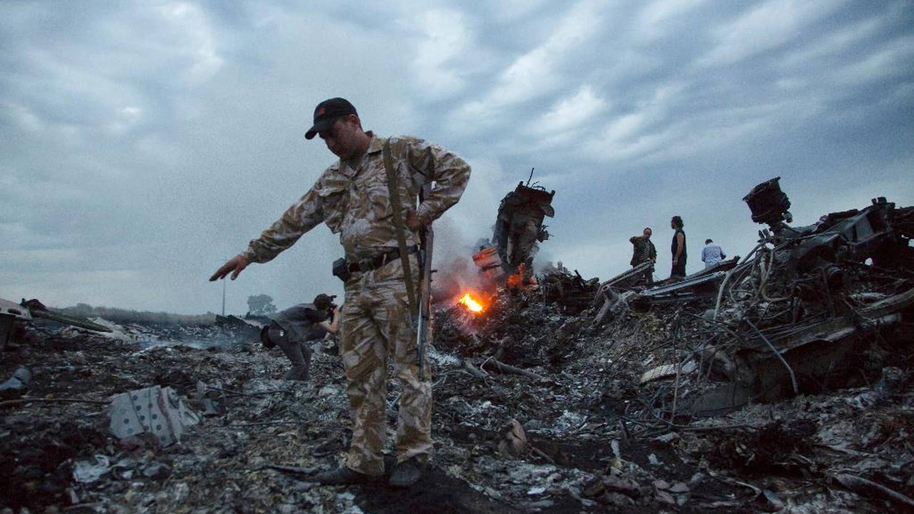 People walk amongst the debris at the crash site of a passenger plane near the village of Grabovo, Ukraine, Thursday, July 17, 2014. Ukraine said a passenger plane carrying 295 people was shot down Thursday as it flew over the country, and both the government and the pro-Russia separatists fighting in the region denied any responsibility for downing the plane. (AP Photo/Dmitry Lovetsky)