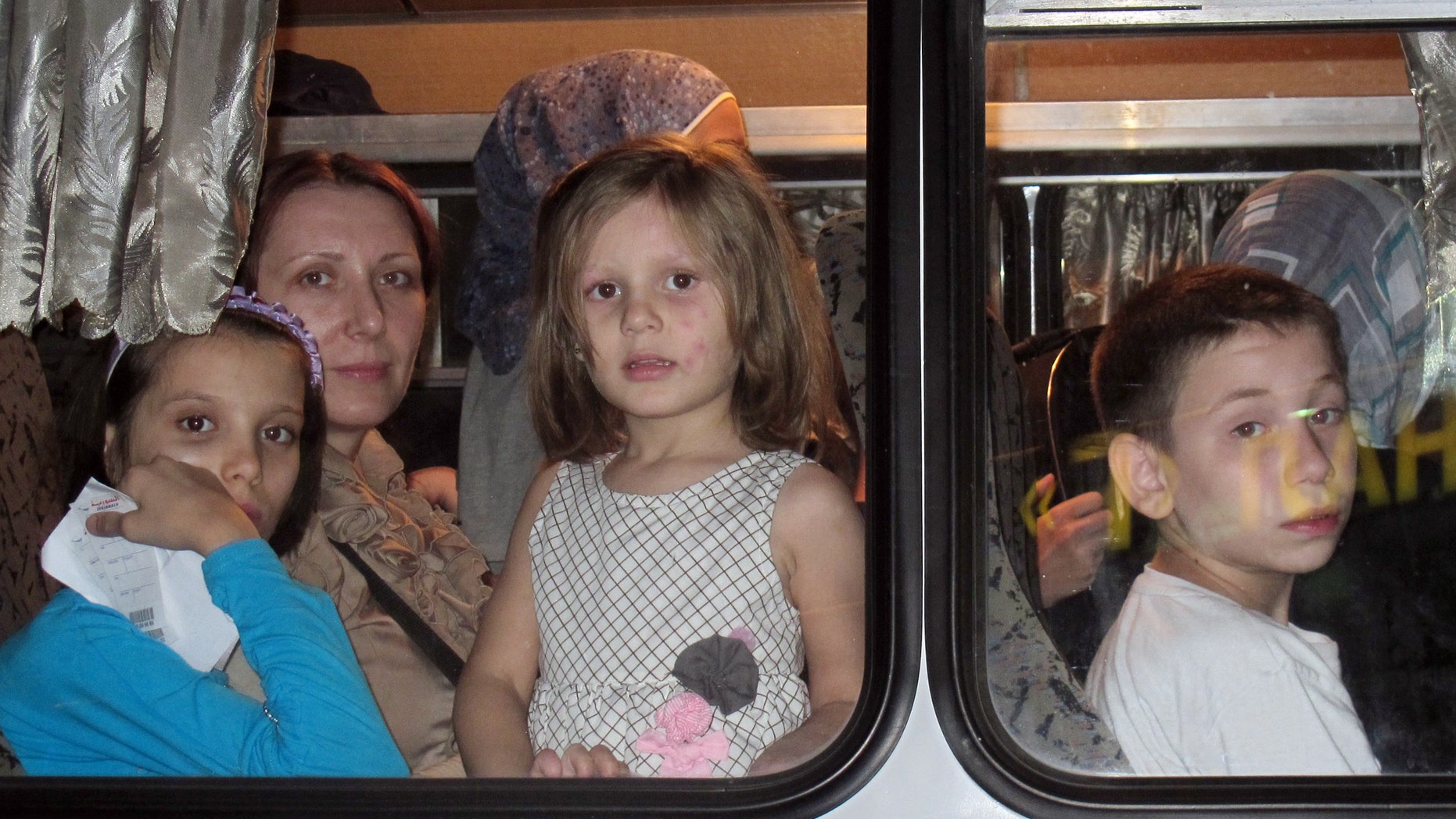 Aug. 1, 2012: Women and their children look out of the window in a Ukrainian Emergency Situations Ministry's bus after arriving at Kiev's Boryspil airport from Syria.