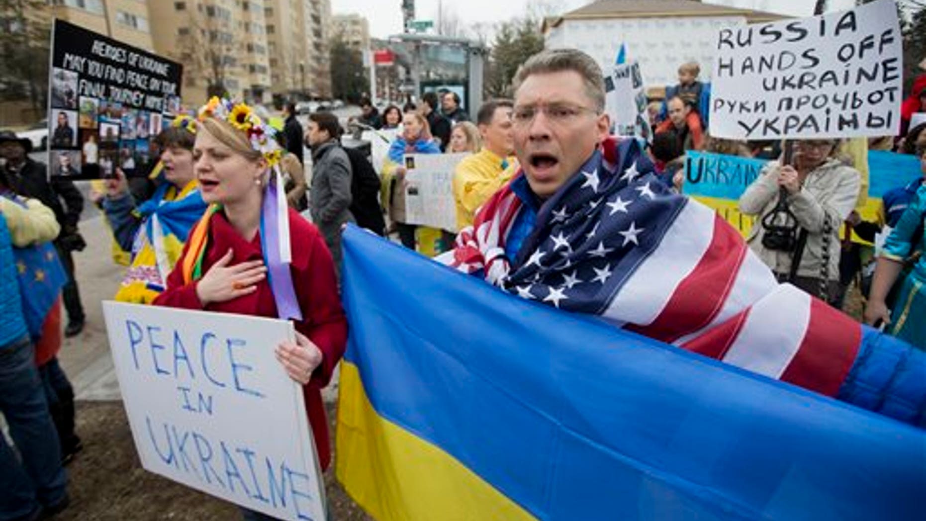 Moscow-born Dmitry Savransky, right, who holds dual citizenship, American and Russian, joins his Ukrainian wife Natalya Seay, left, during a protest rally in front of the Russian embassy, in Washington, Sunday, March 2, 2014. Igniting a tense standoff, Russian forces surrounded a Ukrainian army base Sunday just as the country began mobilizing in response to the surprise Russian takeover of Crimea. Outrage over Russia's tactics mounted in world capitals, with U.S. Secretary of State John Kerry calling on President Vladimir Putin to pull back from "an incredible act of aggression." (AP Photo/Manuel Balce Ceneta)