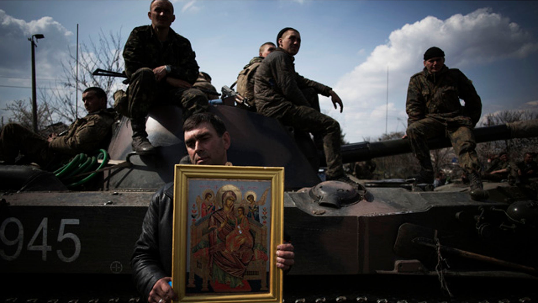 April 16, 2014: A local resident holds an Orthodox icon in front of an armored vehicle and soldiers of the Ukrainian Army, as they are blocked by people on their way to the town of Kramatorsk. Pro-Russian insurgents commandeered six Ukrainian armored vehicles along with their crews and hoisted Russian flags over them Wednesday, dampening the central government's hopes of re-establishing control over restive eastern Ukraine. (AP Photo/Manu Brabo)