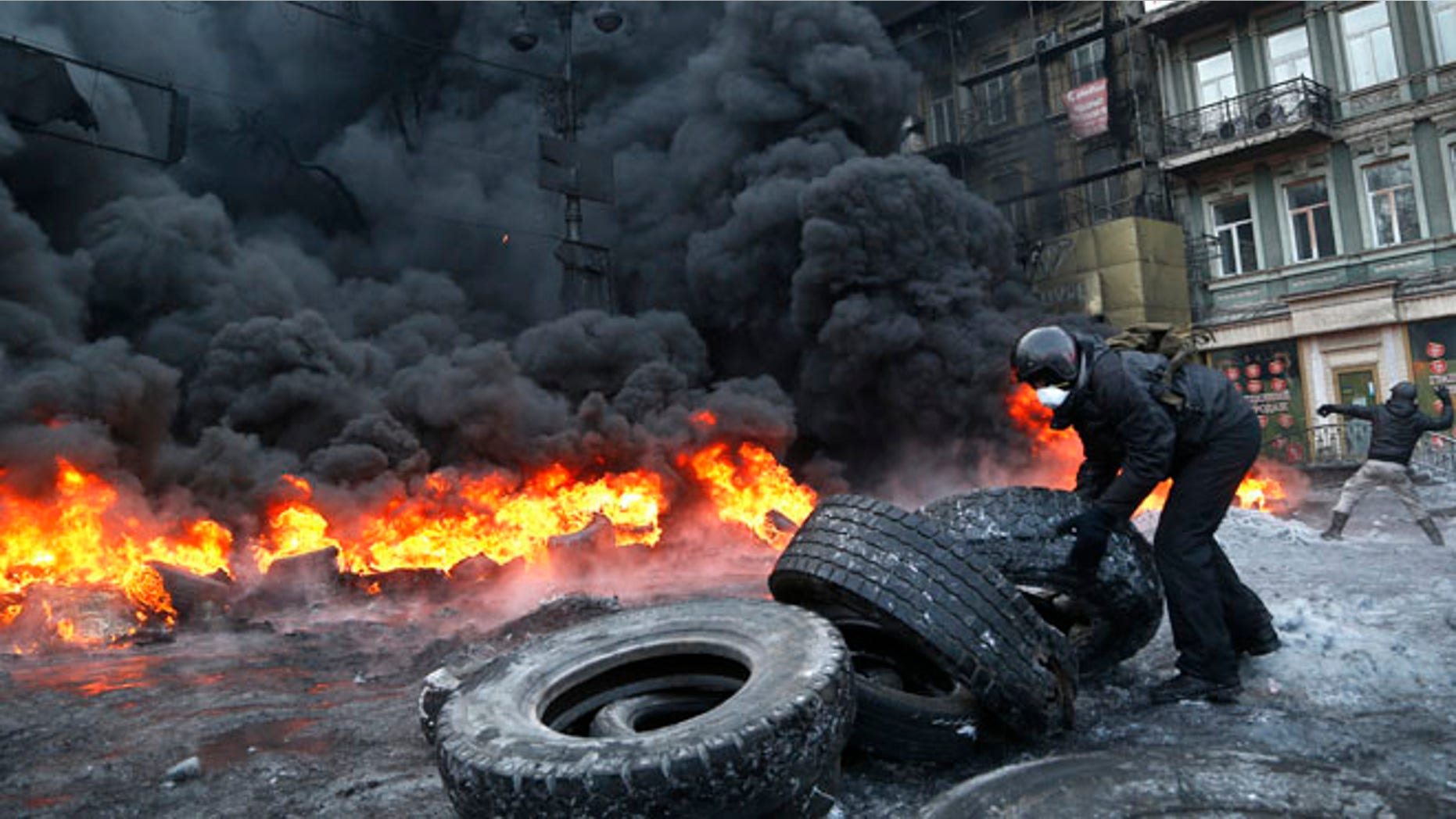 Jan. 25, 2014: A protester prepares to throw a tire onto a fire during clashes with police in central Kiev, Ukraine, early Saturday.