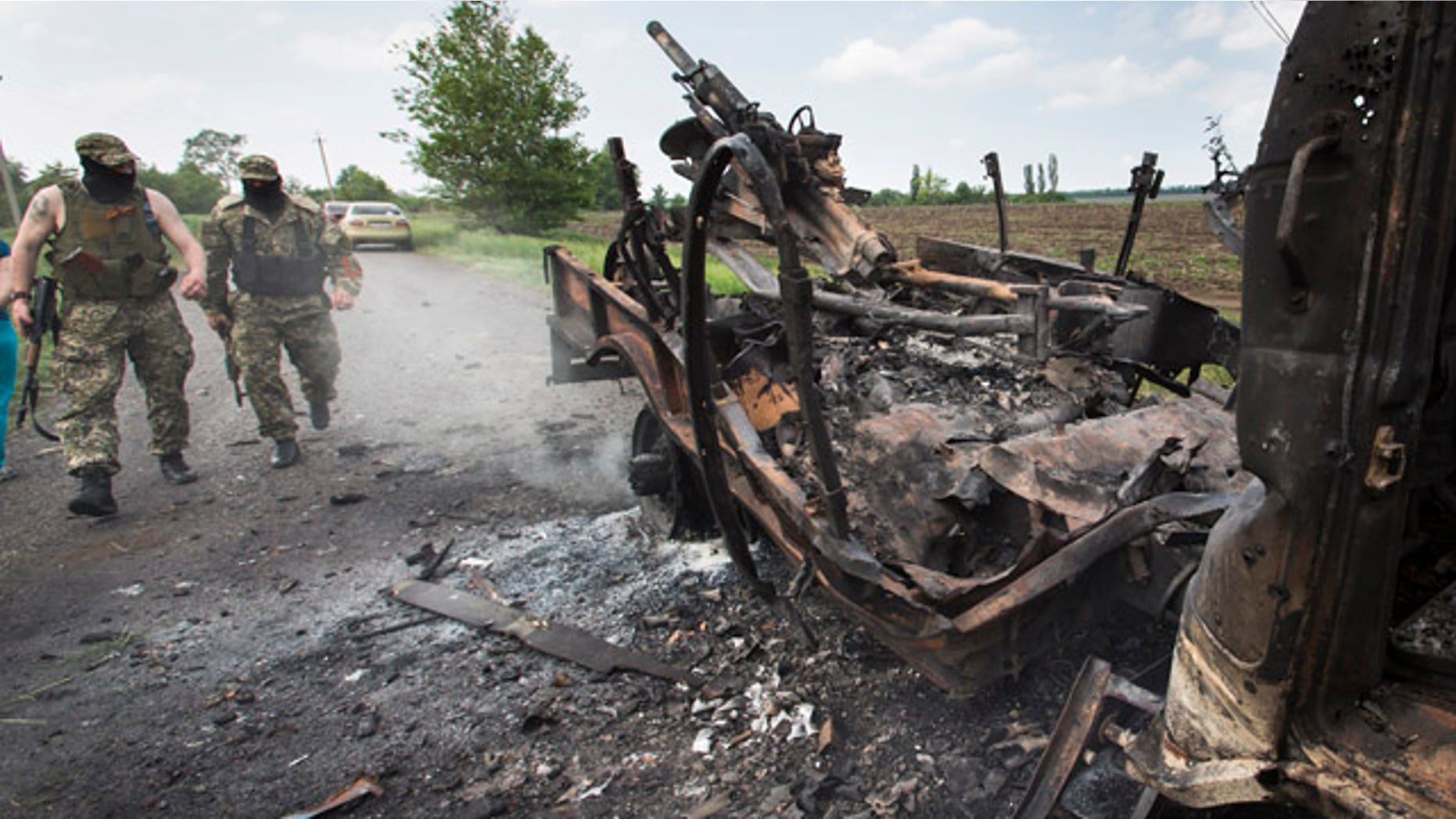 May 14, 2014: Two armed pro-Russians walk towards a seized military track with a mortar atop that was set alight during fighting between pro-Russian militants and government troops at Oktyabrskoye village, about 12 miles from Kramatorsk in eastern Ukraine. (AP Photo/Alexander Zemlianichenko)