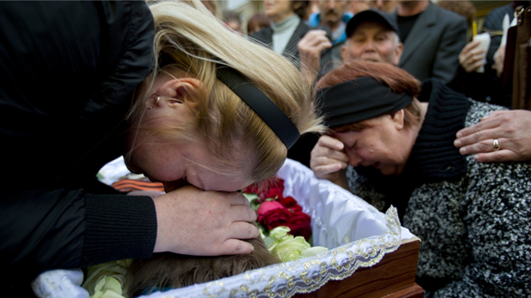 May 6, 2014: Relatives cry around the coffin of 17 year-old Vadim Papura during a religious service outside his apartment block, in Odessa, Ukraine. Papura died after jumping out of the trade union building in an attempt to escape a fire that killed most of the 40 people that died after riots erupted last Friday. (AP Photo/Vadim Ghirda)