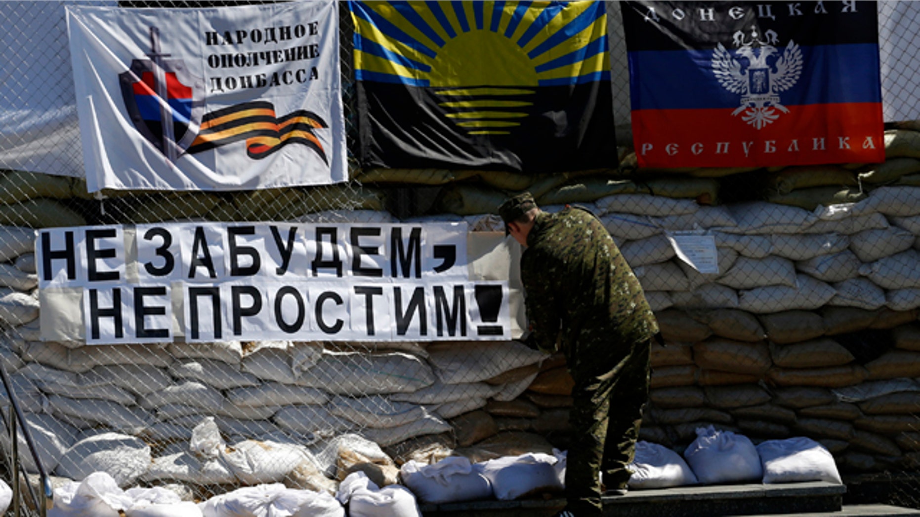 May 8, 2014: A pro-Russian gunman sets a banner which reads 'Do not forget, do not forgive!' in front of the city hall decorated with flags of the self-proclaimed Donetsk People's Republic, in the center of Slovyansk, eastern Ukraine (AP Photo/Darko Vojinovic)
