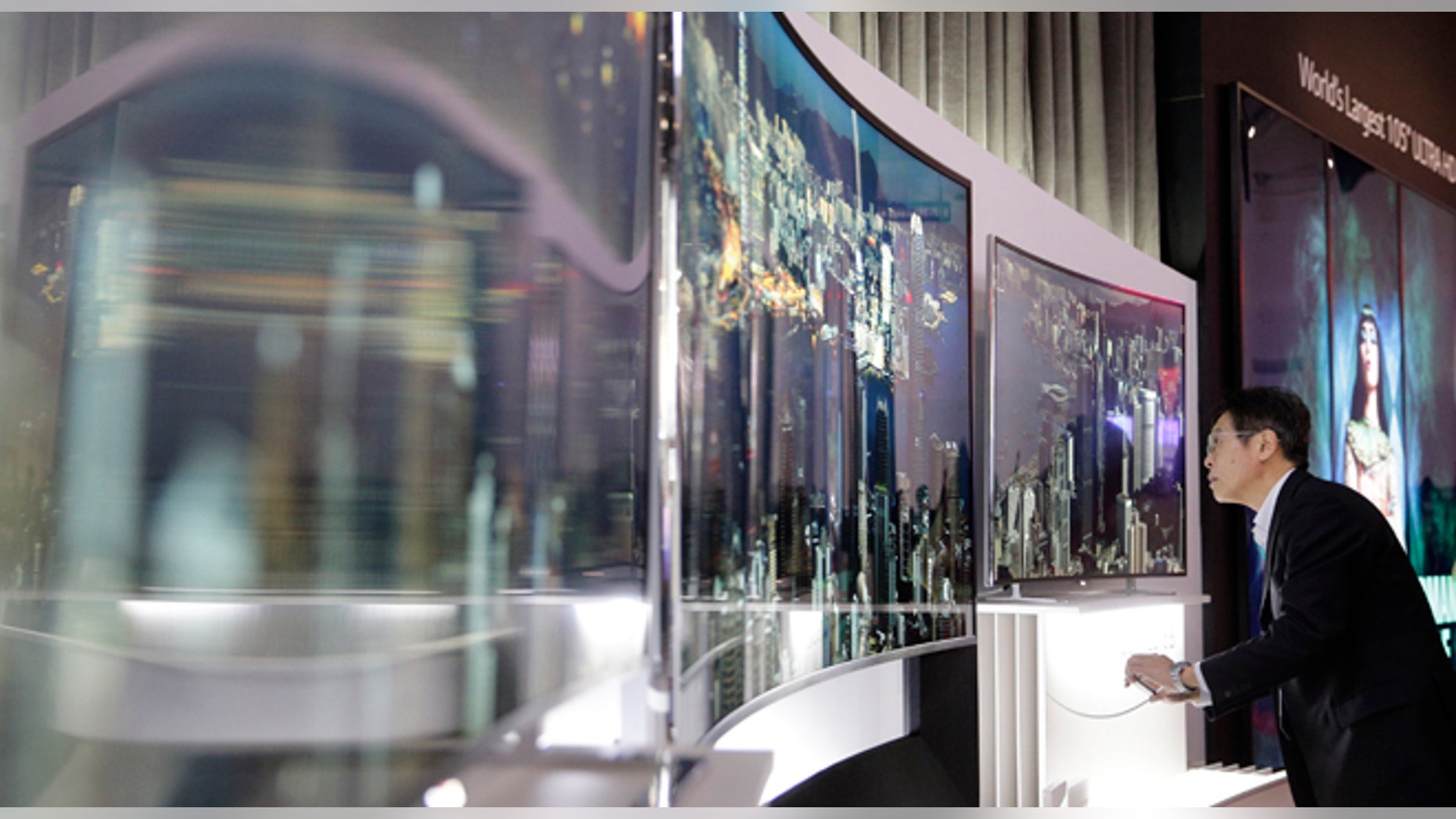 A show attendee looks at LG's 105-inch curved ultra HD TV at the International Consumer Electronics Show(CES) on Tuesday, Jan. 7, 2014, in Las Vegas. (AP Photo/Jae C. Hong)