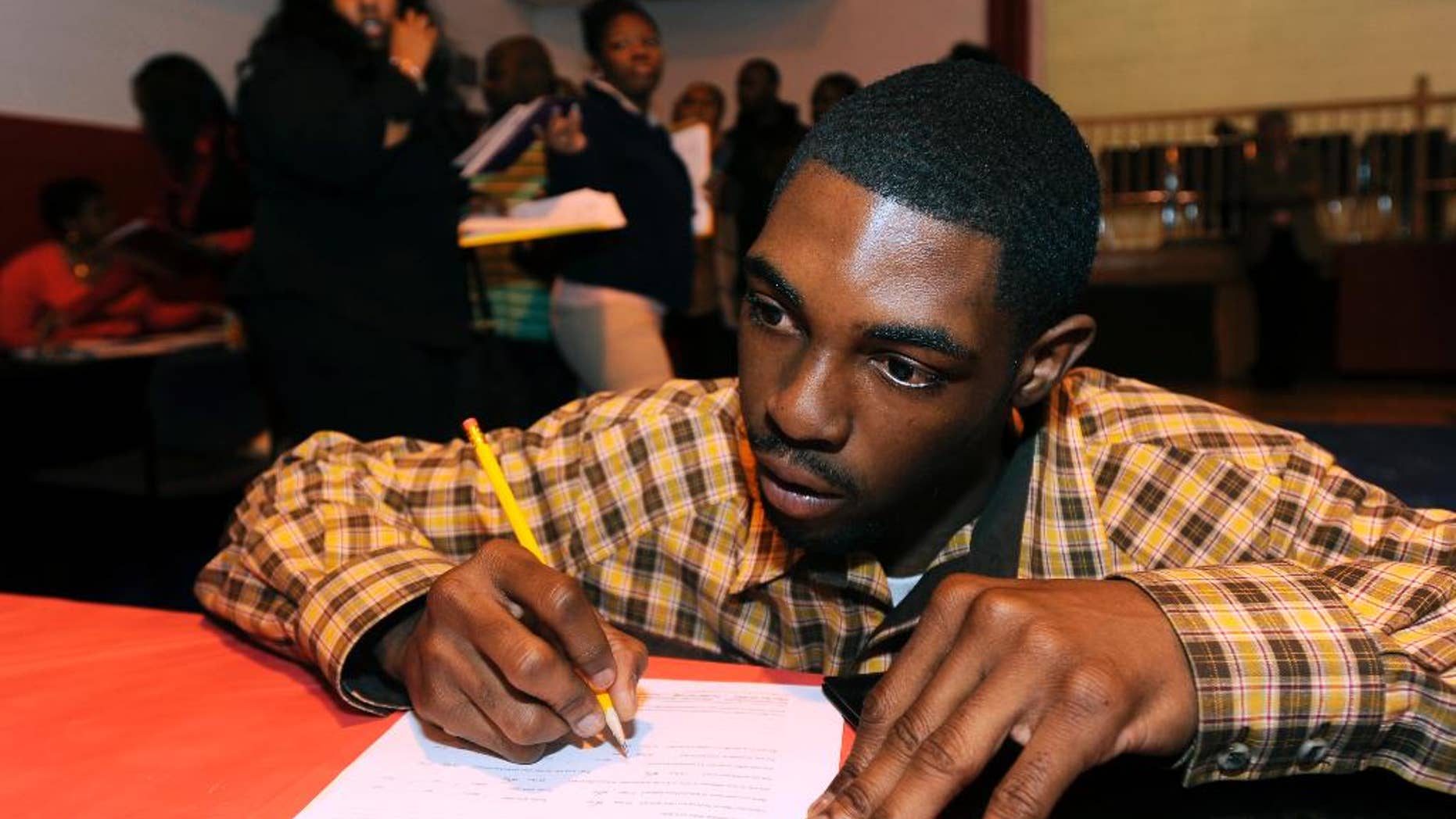 In this April 23, 2014 photo, Davon Tremble, of Detroit, fills out an application at a job fair at the Matrix Center in Detroit. The Labor Department reports the number of people who applied for unemployment benefits last week on Thursday, May 15, 2014. (AP Photo/The Detroit News, David Coates)