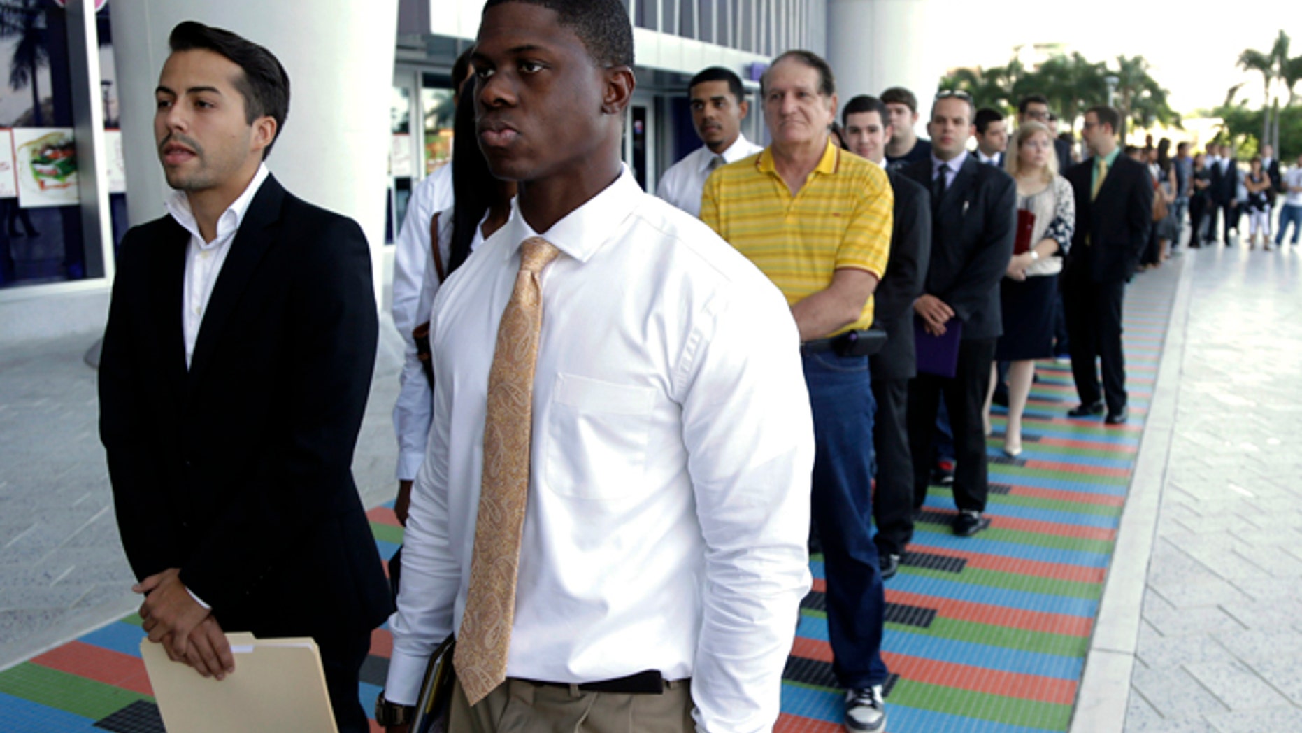 FILE - In this Wednesday, Oct. 23, 2013, file photo, Luis Mendez, 23, left, and Maurice Mike, 23, wait in line at a job fair held by the Miami Marlins, at Marlins Park in Miami. Employers added a scant 74,000 jobs in December after averaging 214,000 in the previous four months. The Labor Department said Friday, Jan. 10, 2014, that the unemployment rate fell from 7 percent in November to 6.7 percent, its lowest level since October 2008. But the drop occurred mostly because many Americans stopped looking for jobs. Once people without jobs stop looking for one, the government no longer counts them as unemployed. (AP Photo/Lynne Sladky, File)