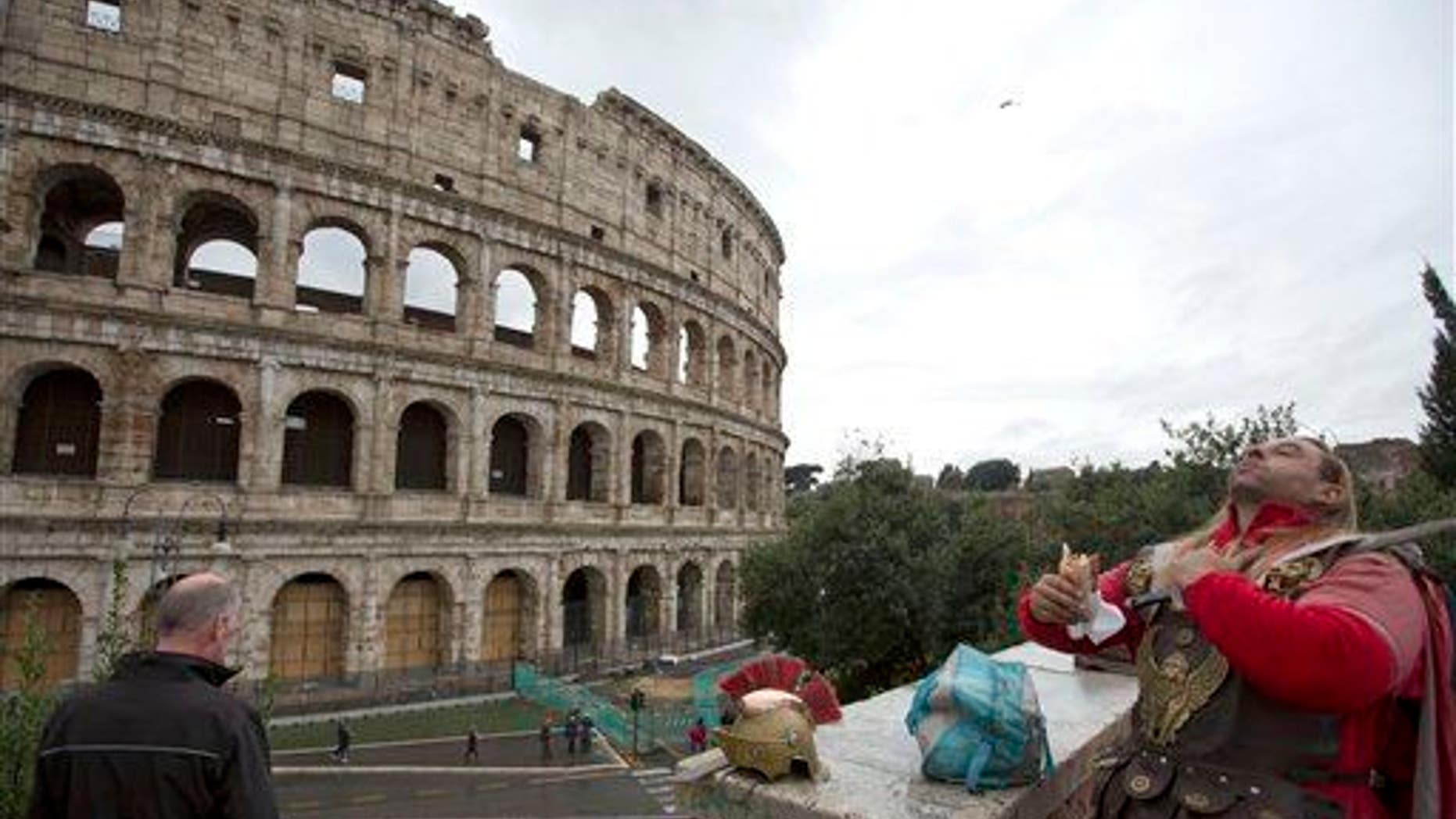 A man dressed as a gladiator enjoys his lunch in front of Rome's Colosseum, Friday Nov. 7, 2014.
