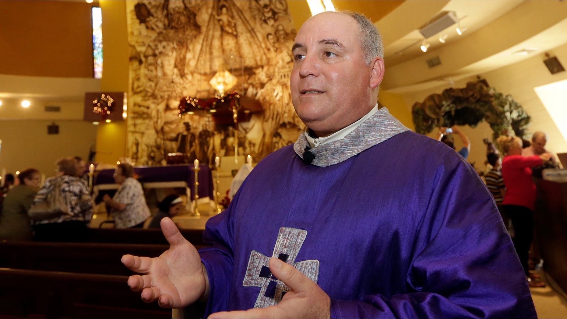In this photo taken Thursday, Dec. 18, 2014, Rev. Juan Rumin Dominguez talks to a reporter at Our Lady of Charity Catholic church in Miami. Many Catholics have expressed pride in seeing Francis stirring hopes of progress in communist Cuba, but some Cuban-Americans say their spiritual leader betrayed them (AP Photo/Alan Diaz)