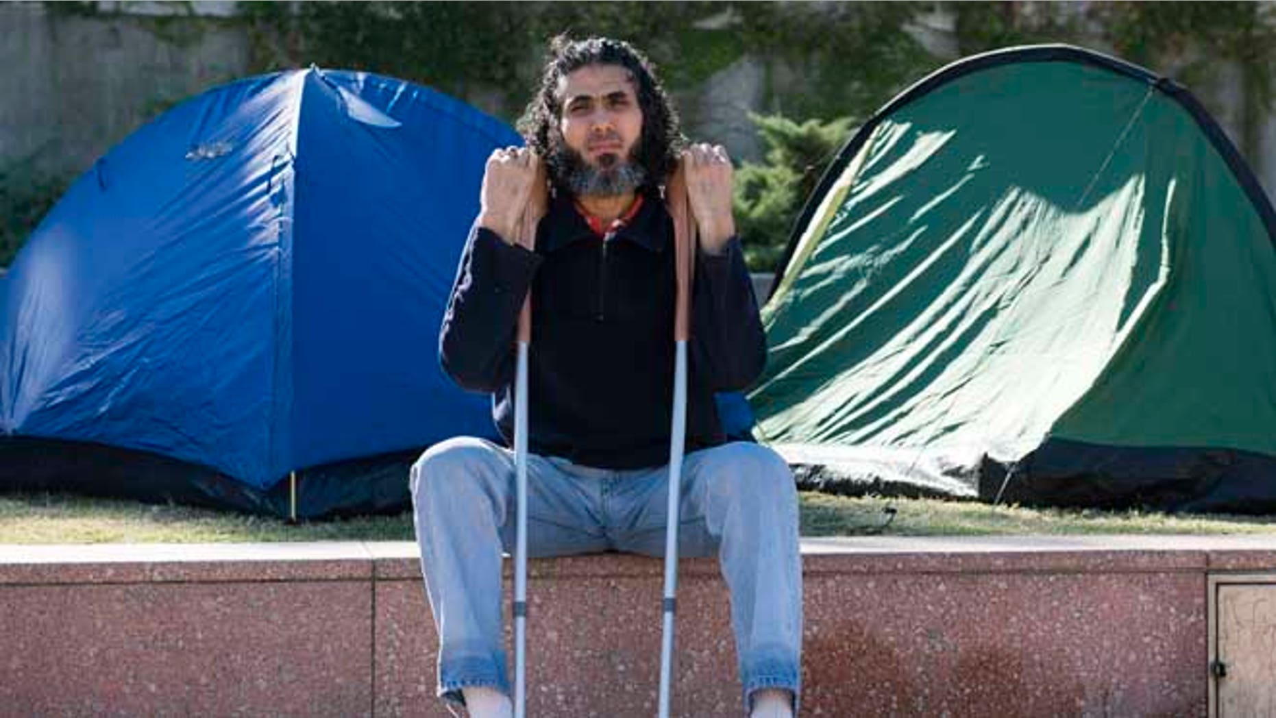 In this May 5, 2015 photo, former Guantanamo detainee Abu Wa'el Dhiab from Syria sits in front of the U.S. embassy while visiting former fellow detainees who were demanding financial assistance from the U.S., in Montevideo, Uruguay. Dhiab, who resettled in Uruguay, was briefly hospitalized Monday, Sept. 5, 2016, after becoming weak from a hunger strike. Dhiab is demanding that he be allowed to leave the South American country. Uruguay took in Dhiab and five other former Guantanamo prisoners for resettlement in 2014. (AP Photo/Matilde Campodonico)