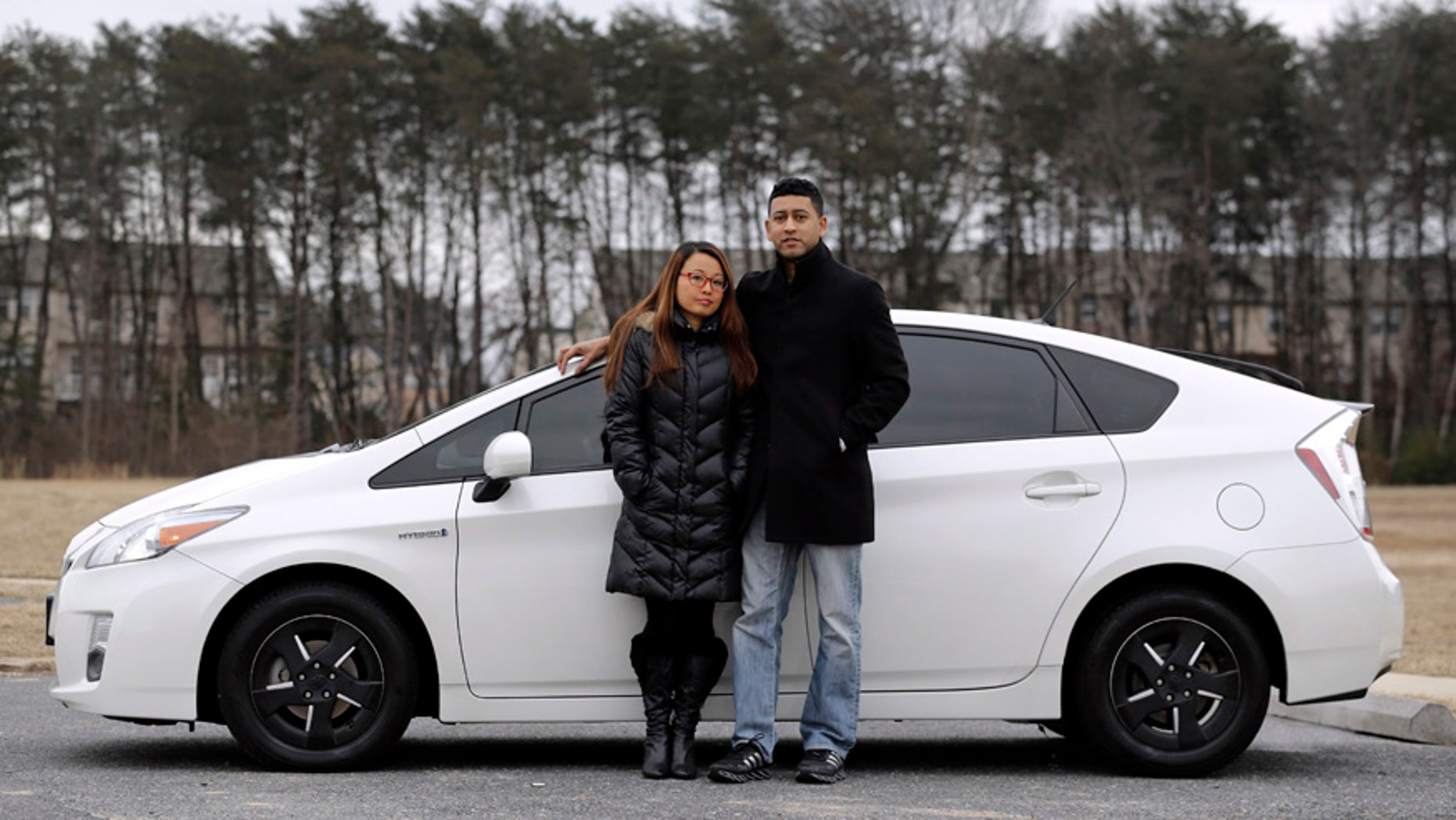 In this Feb. 14, 2015 picture, Eri and John Castro pose in front of their 2011 Toyota Prius in Glen Burnie, Md. The Castros bought the pre-owned car last year, only to find out after they got it home that it was under recall because it could stall without warning. (AP Photo/Patrick Semansky)