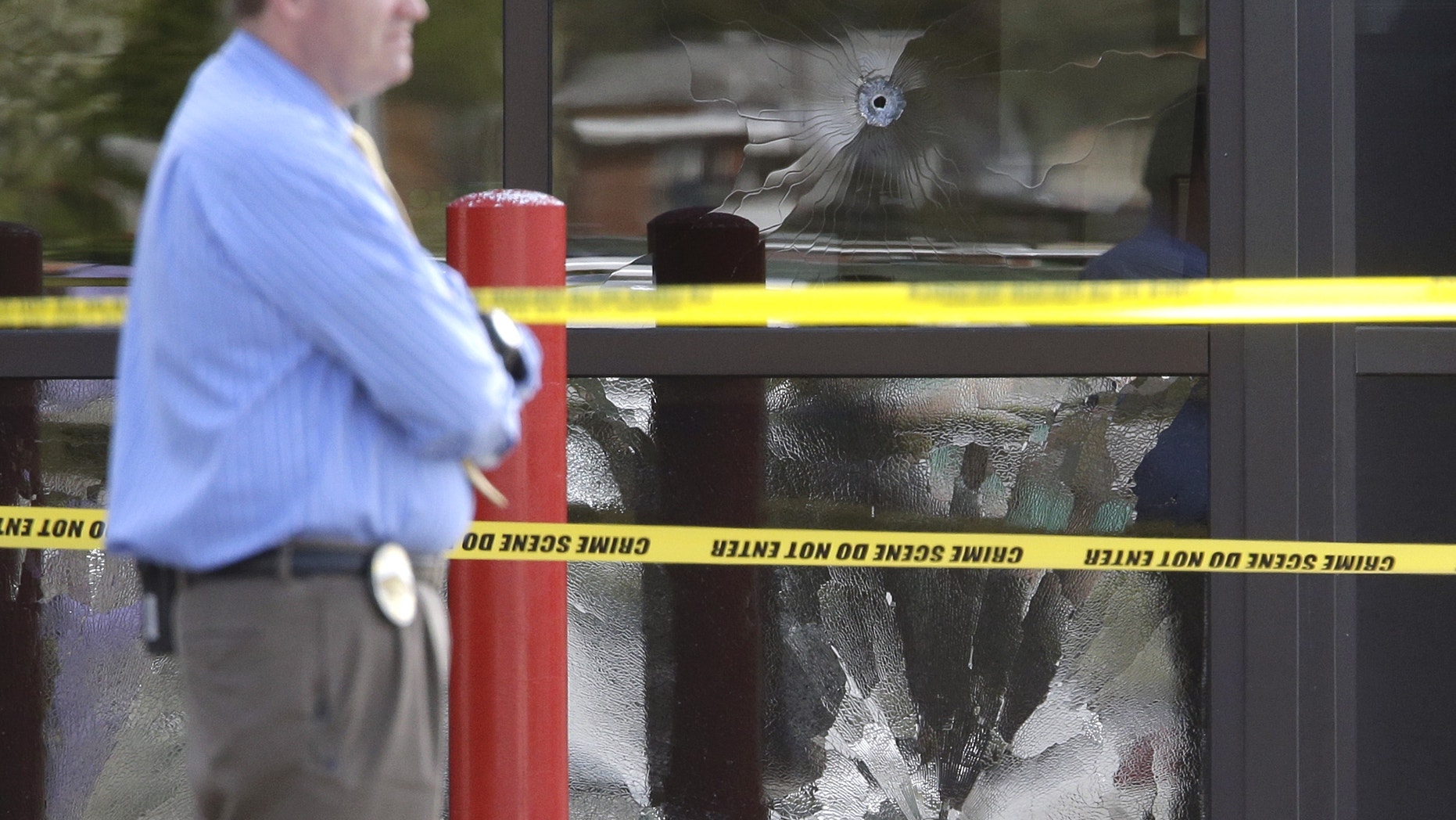 April 29, 2013: A West Valley City Police Officer stands near a bullet shattered window at the West Valley City Police Department in West Valley City, Utah.