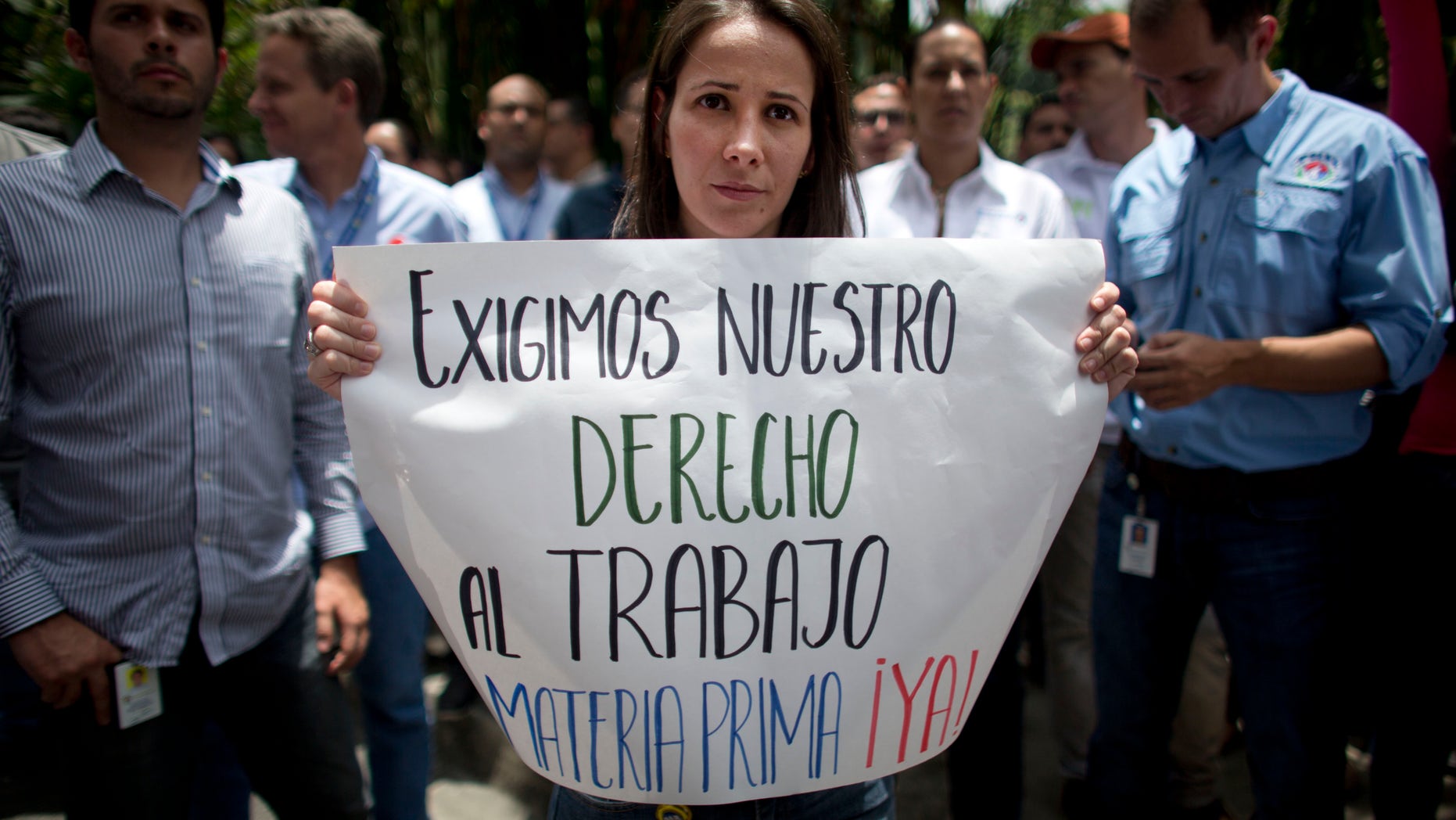 A Polar worker holds a sign that reads in Spanish: "We demand our right to work. Raw material now!" during a protest by workers who fear losing their jobs, outside company headquarters in Caracas, Venezuela, Friday, April 22, 2016. Polar, the largest producer of beer in the country, said Thursday the lack of imported raw materials could force them to stop producing beer starting April 29, when their current stock of malted barley would run out. (AP Photo/Ariana Cubillos)