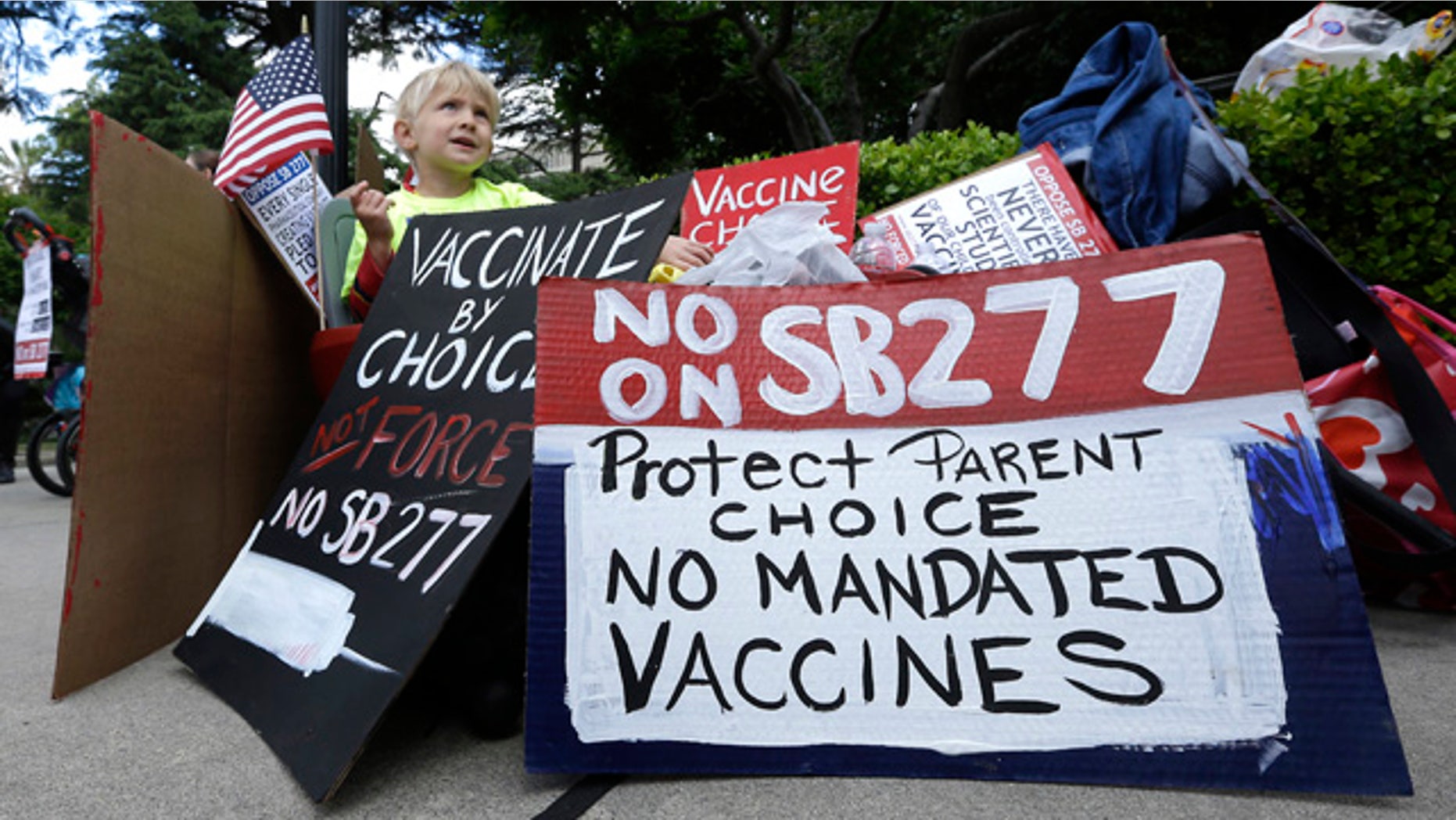 April 8, 2015: Zach Bingham, 6, sits among protest signs at against a measure requiring California schoolchildren to get vaccinated at a Capitol rally in Sacramento. (AP Photo/Rich Pedroncelli)