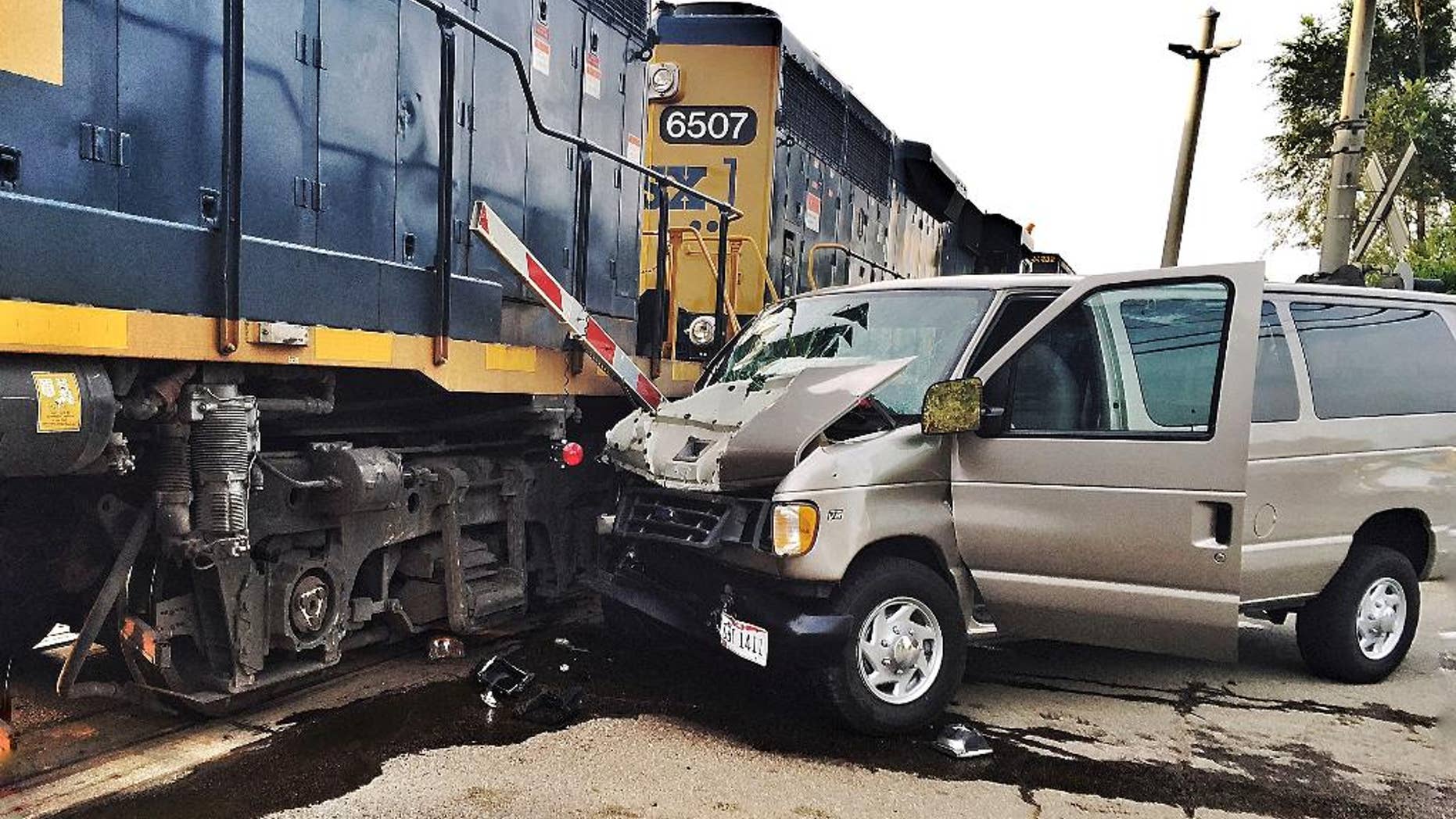In this Tuesday, July 28, 2015 photo, a van rests against a train engine after a collision in Middletown, Ohio. An adult was killed and 10 others were injured when the van, transporting students to evening vacation Bible school, crashed into the side of the train. The Ohio State Highway Patrol said the gates were down and the warning lights activated at the crossing when the van approached. (Todd Jackson/WHIO-TV) MANDATORY CREDIT.