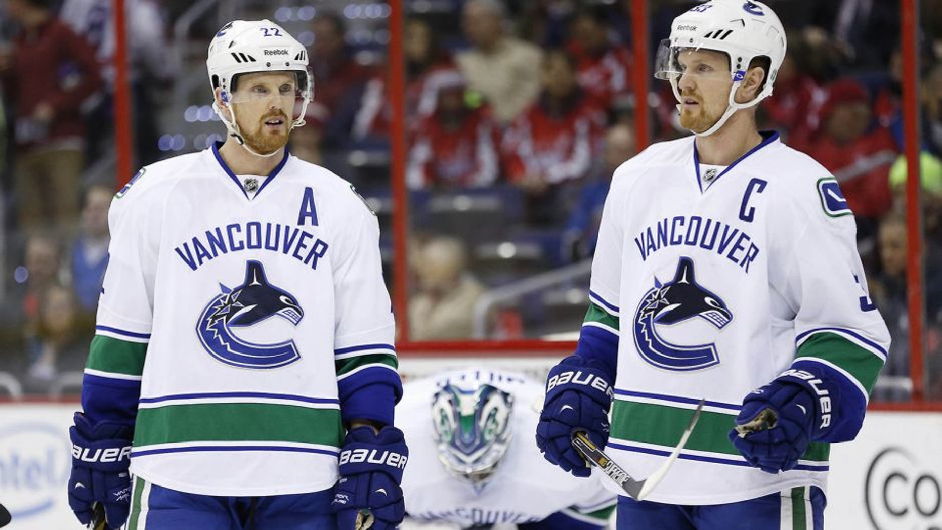 Dec 2, 2014; Washington, DC, USA; Vancouver Canucks left wing Daniel Sedin (22) and Canucks center Henrik Sedin (33) stand on the ice against the Washington Capitals in the first period at Verizon Center. Mandatory Credit: Geoff Burke-USA TODAY Sports