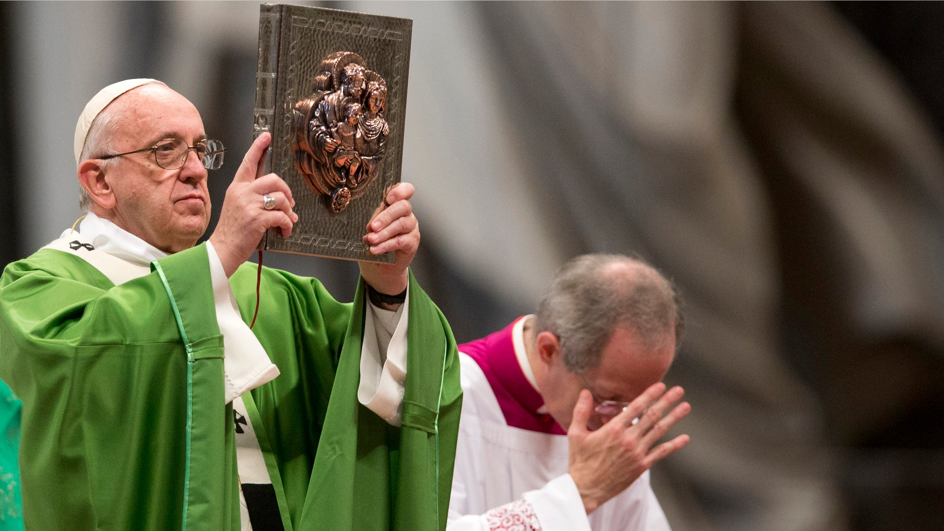 Pope Francis holds the Gospel Book as he celebrates a Mass to mark the end of the Synod of bishops, in St.Peter's Basilica at the Vatican, Sunday, Oct. 25, 2015. Catholic bishops called Saturday for a more welcoming church for cohabitating couples, gays and Catholics who have divorced and civilly remarried, endorsing Pope Francis' call for a more merciful and less judgmental church. (AP Photo/Alessandra Tarantino)