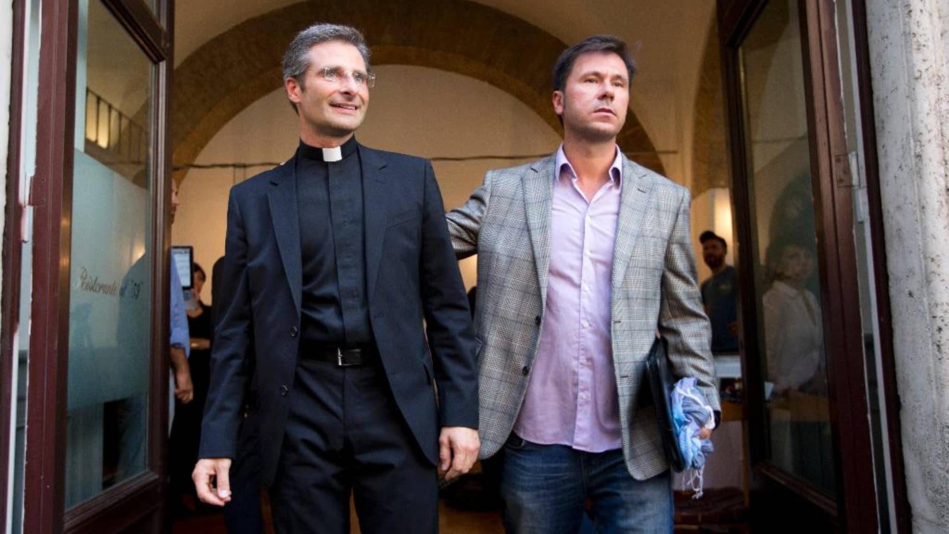 Monsignor Krzysztof Charamsa, left, and his boyfriend Eduard, surname not given, pose for a photo after a press conference in Rome Saturday. (AP Photo/Alessandra Tarantino)