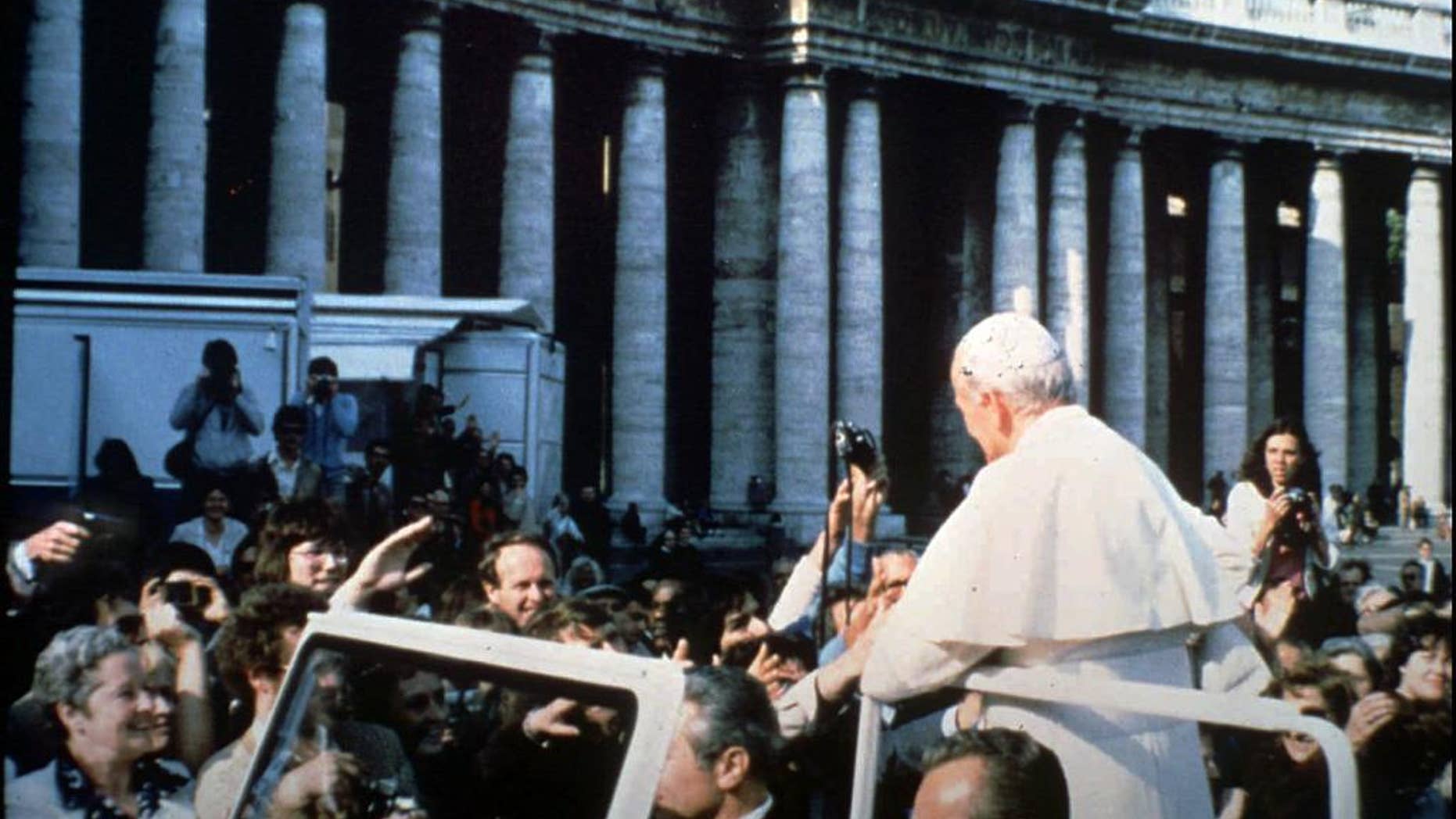 In this May 13, 1981 file photo provided by Vatican paper L'Osservatore Romano, Mehmet Ali Agca, left, holds a Browning HP 9mm handgun to shoot Pope Jonh Paul II at the Vatican. Alitalia Flight 488 landed in Krakow, Poland on Tuesday, March 18, 2014 with some very special cargo on board: The gun used to shoot Pope John Paul II. Monsignor Dariusz Ras, the Polish priest who runs the John Paul II museum in the late pope's childhood home in Wadowice, transported the pistol from Rome to Poland for the museum's upcoming exhibit in honor of John Paul's April 27 canonization, Alitalia said. Mehmet Ali Agca used the Browning HP 9mm handgun to shoot John Paul in the abdomen in St. Peter's Square on May 13, 1981. The pope spent nearly three weeks in the hospital recovering. (AP Photo/L'Osservatore Romano)
