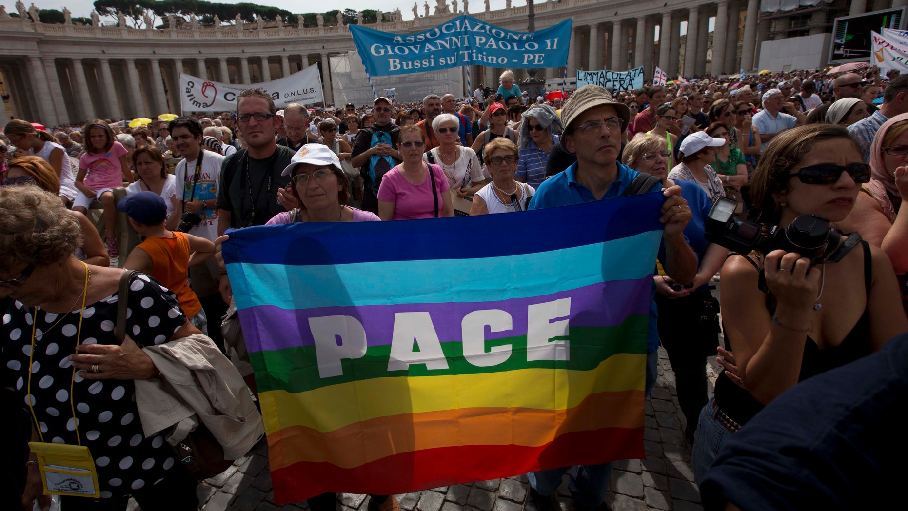 Faithful hold up a rainbow-coloured peace flag with the word "Peace" as they attend Pope Francis' Angelus noon prayer in St. Peter's Square at the Vatican, Sunday, Sept. 8, 2013. On Saturday tens of thousands of people filled St. Peter's Square for a four-hour Syria peace vigil, answering Pope Francis' call for a grassroots cry for peace that was echoed by Christians and non-Christians alike in Syria and in vigils around the world. (AP Photo/Alessandra Tarantino)