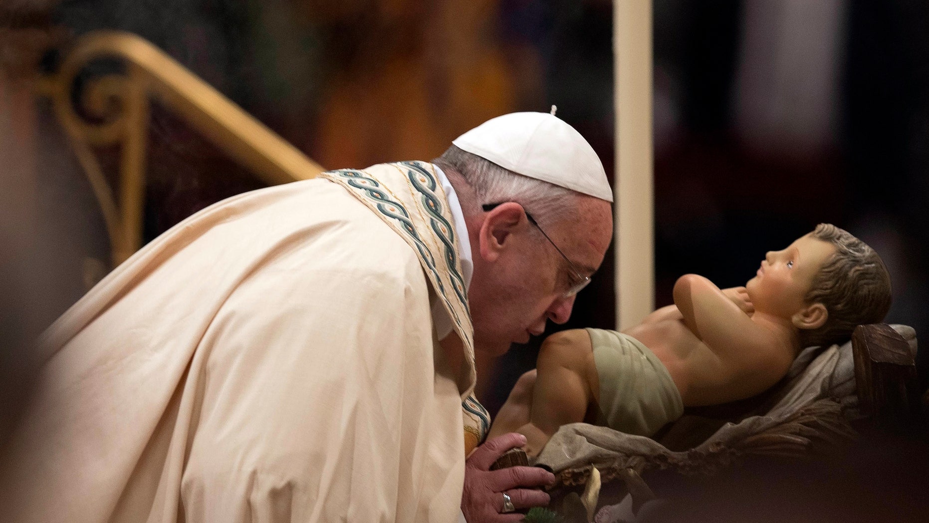 Pope Francis kisses a baby Jesus statue in St. Peter's Basilica at the Vatican, Tuesday, Dec. 31, 2013.