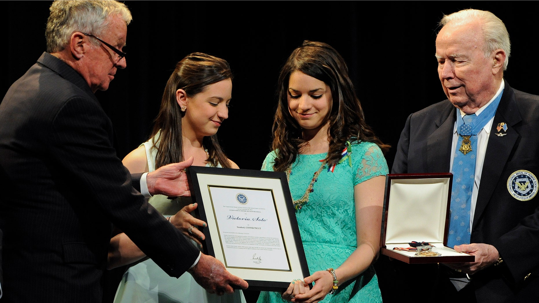 Sisters Jillian Soto, center left, and Carlee Soto, center right, accept the citizen honor of the Congressional Medal of Honor from Medal of Honor Recipient presenters, Thomas Kelley, left, and Bruce Crandall, right, on behalf of their late sister Victoria Soto in Newtown, Conn., Monday, May 6, 2013. The Congressional Medal of Honor Society says Rachel D'Avino, Dawn Hochsprung, Anne Marie Murphy, Lauren Rousseau, Mary Sherlach and Victoria Soto exemplified courage, sacrifice and selflessness in trying to protect students from the gunman at Sandy Hook Elementary School. (AP Photo/Jessica Hill)